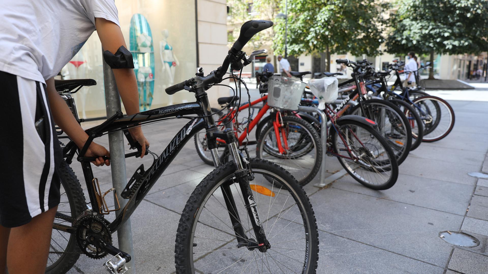 Un ciudadano pone el candado a una bicicleta en Pamplona