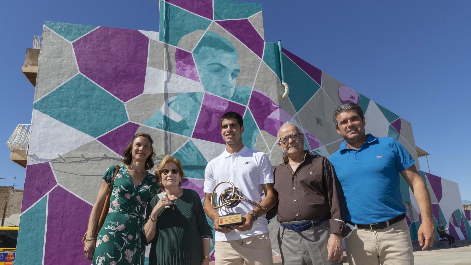 Carlos Alcaraz posa junto a su familia delante del grafiti