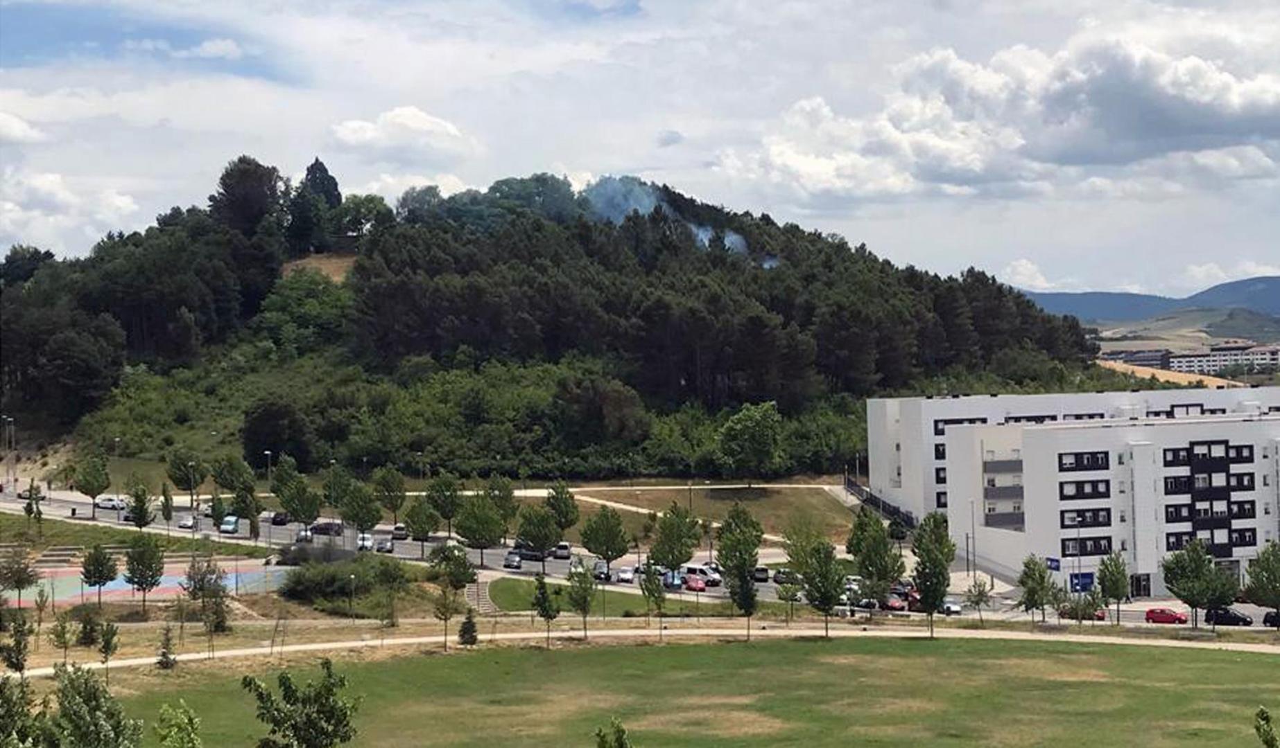 Bomberos de Navarra trabajan para extinguir un pequeño incendio registrado este lunes en una zona de bosque situada entre la nueva escuela infantil de Lezkairu y los depósitos de Mendillorri. En las labores de extinción trabaja un helicóptero.