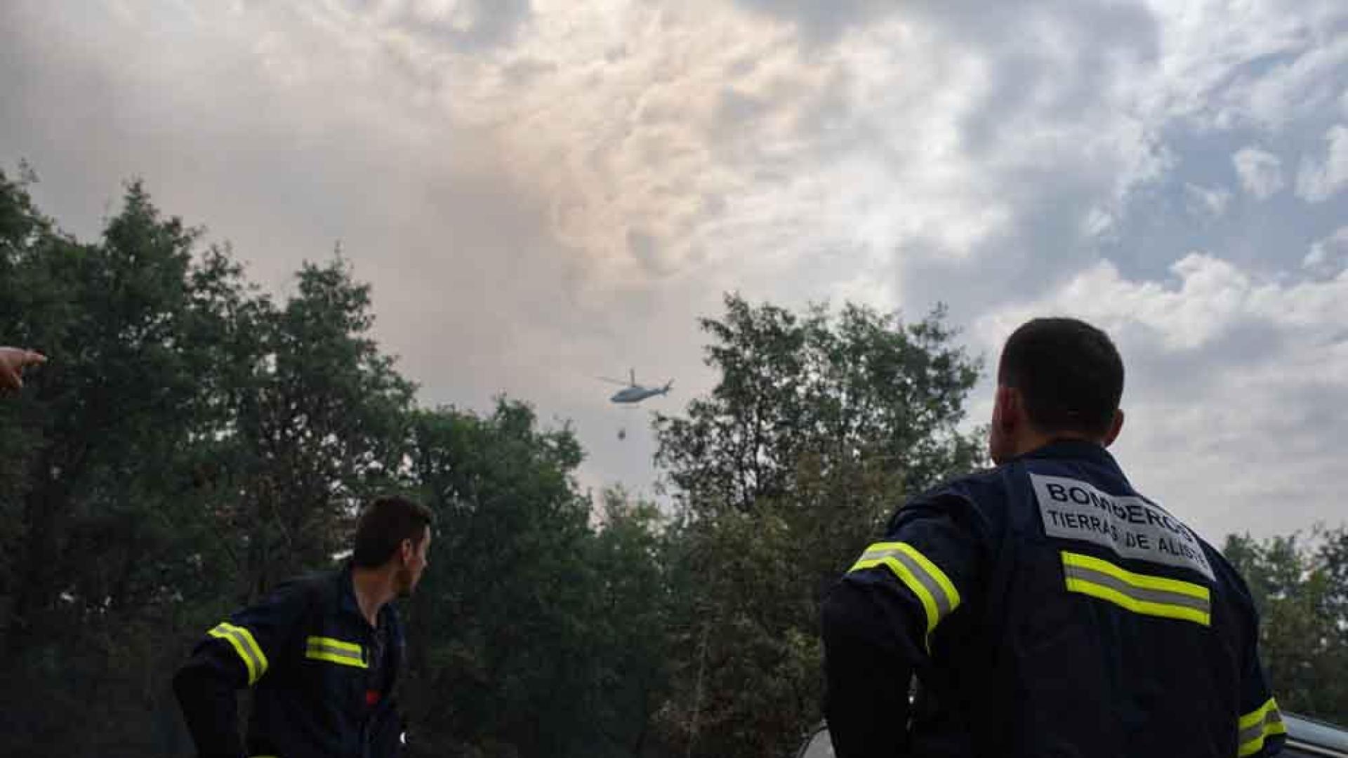 Dos bomberos observan un helicóptero trabajando en el incendio de la Sierra de la Culebra