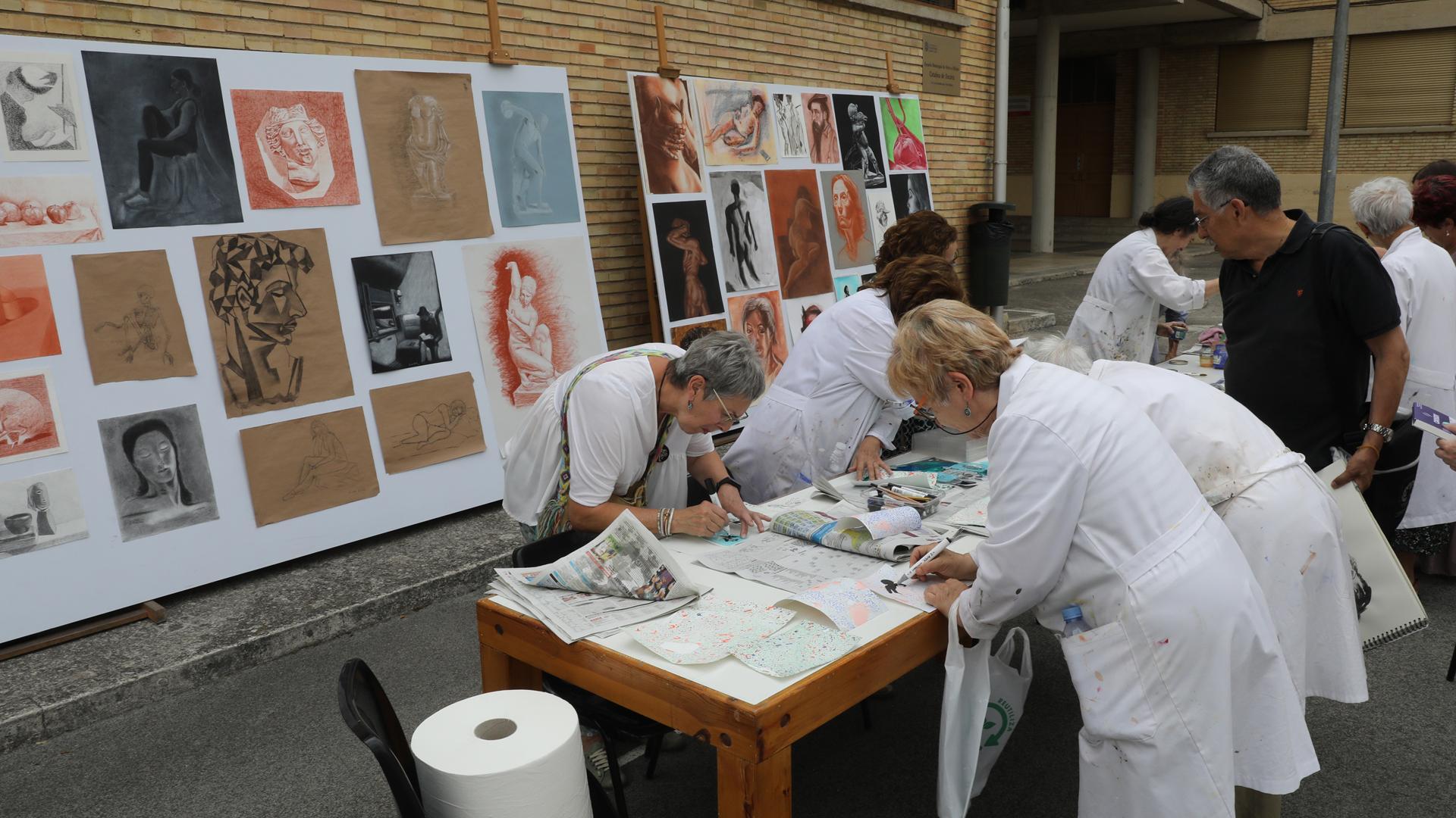 Alumnas de la escuela trabajando en sus obras. Al fondo, las obras de arte de los alumnos del curso de Pintura
