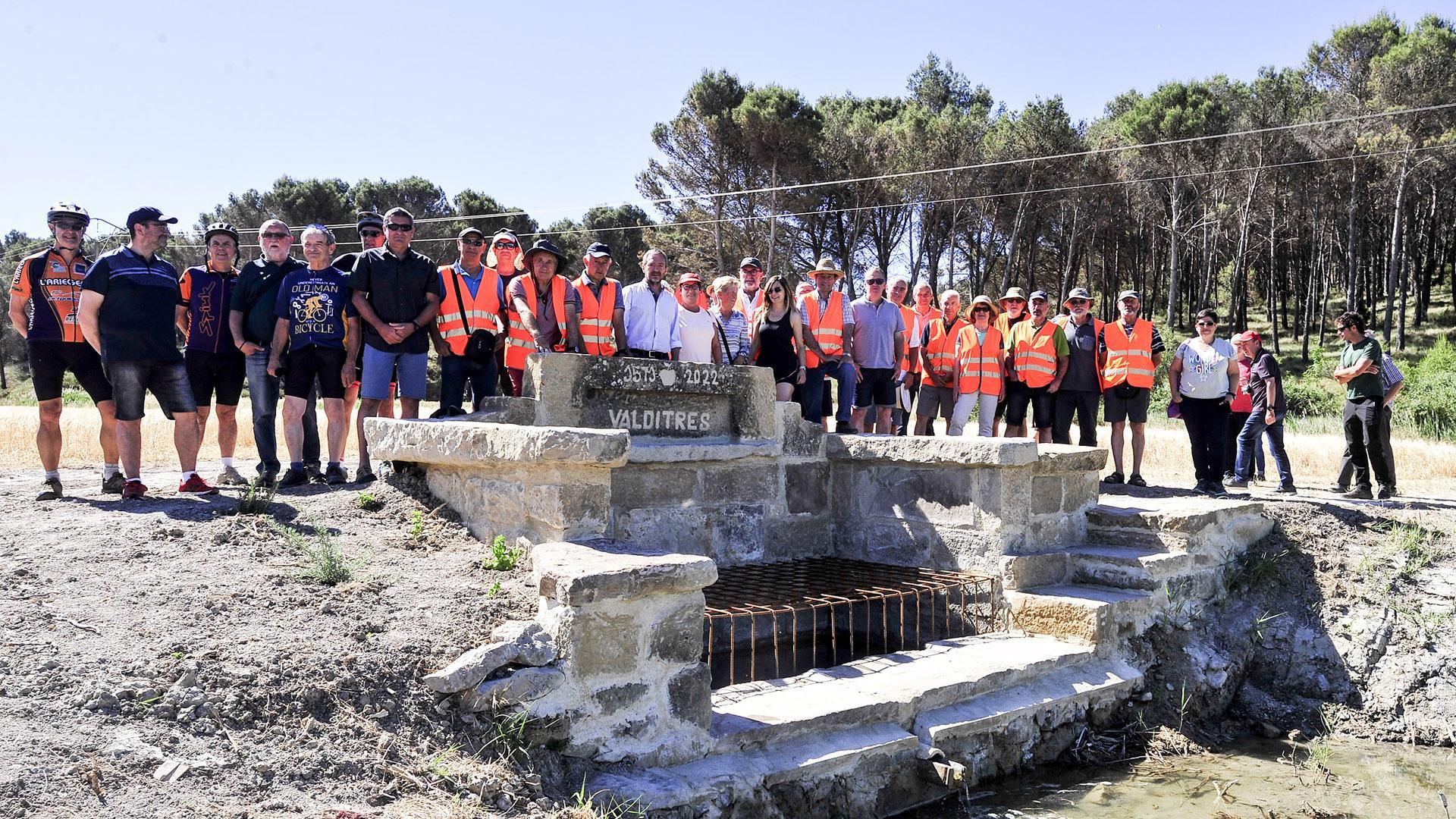 El grupo de personas voluntarias junto a la fuente que han recuperado tras semanas de intenso trabajo