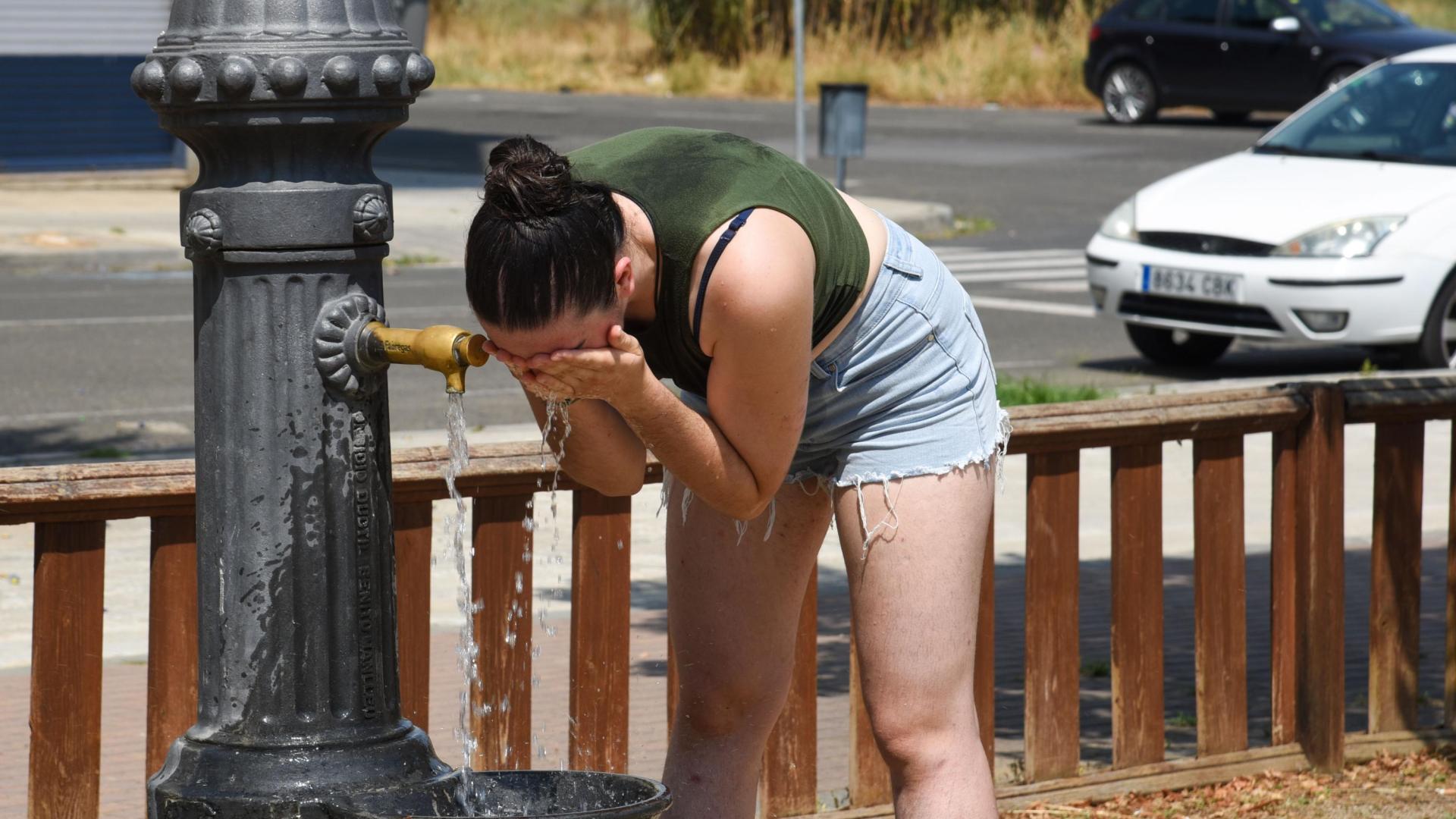 Una joven se refresca en una fuente