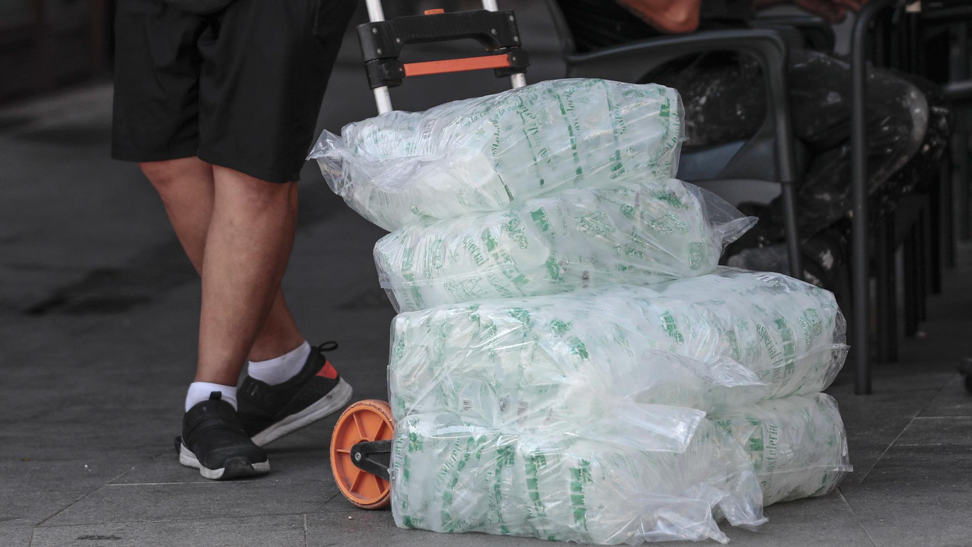 Un repartidor con varias bolsas de cubitos de hielo