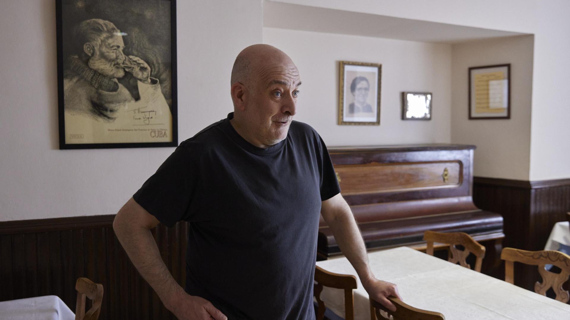 Iñaki Urdiroz, propietario del Hostal Burguete, en el comedor junto al piano y el cuadro de Hemingway.	 JESÚS GARZARON