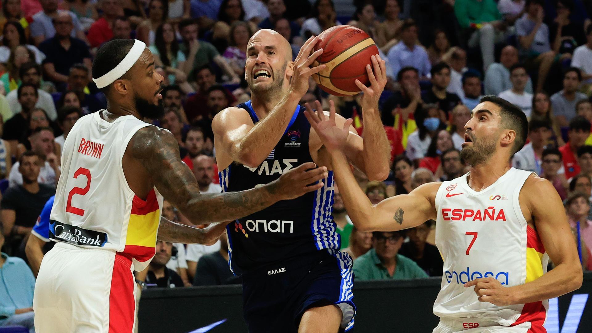 El base de la selección griega de baloncesto Nick Calathes (c) entra a canasta defendido por Jaime Fernández (d) y Lorenzo Brown (i), ambos de la selección española, en el segundo amistoso de preparación para el Eurobasket