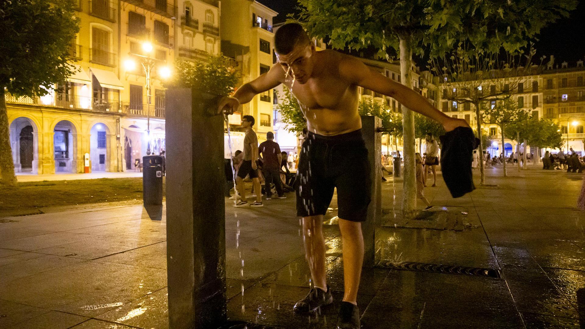 Un joven aprovecha el agua de una de las fuentes de la Plaza del Castillo para refrescarse