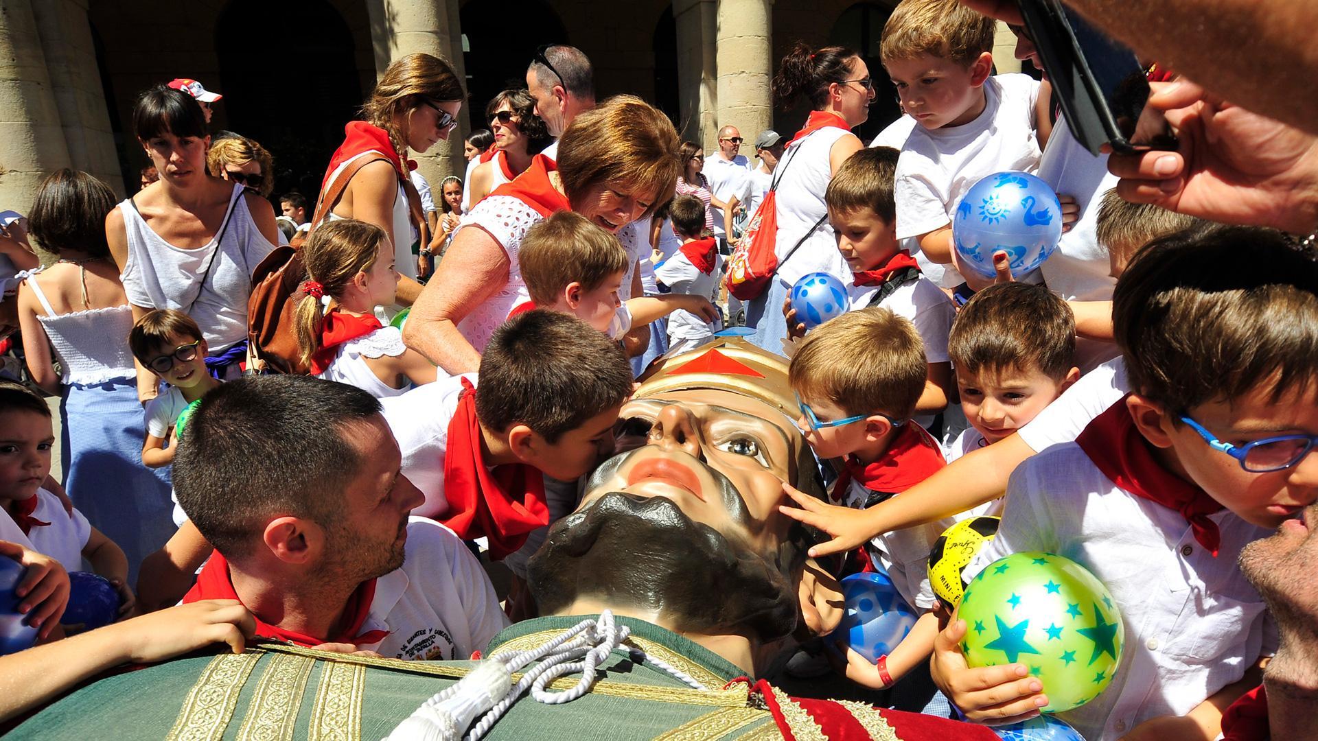 Un grupo de niños se despide de la figura de uno de los gigantes entre besos y caricias cuando los miembros de la comparsa lo tumbaron antes de guardarlos