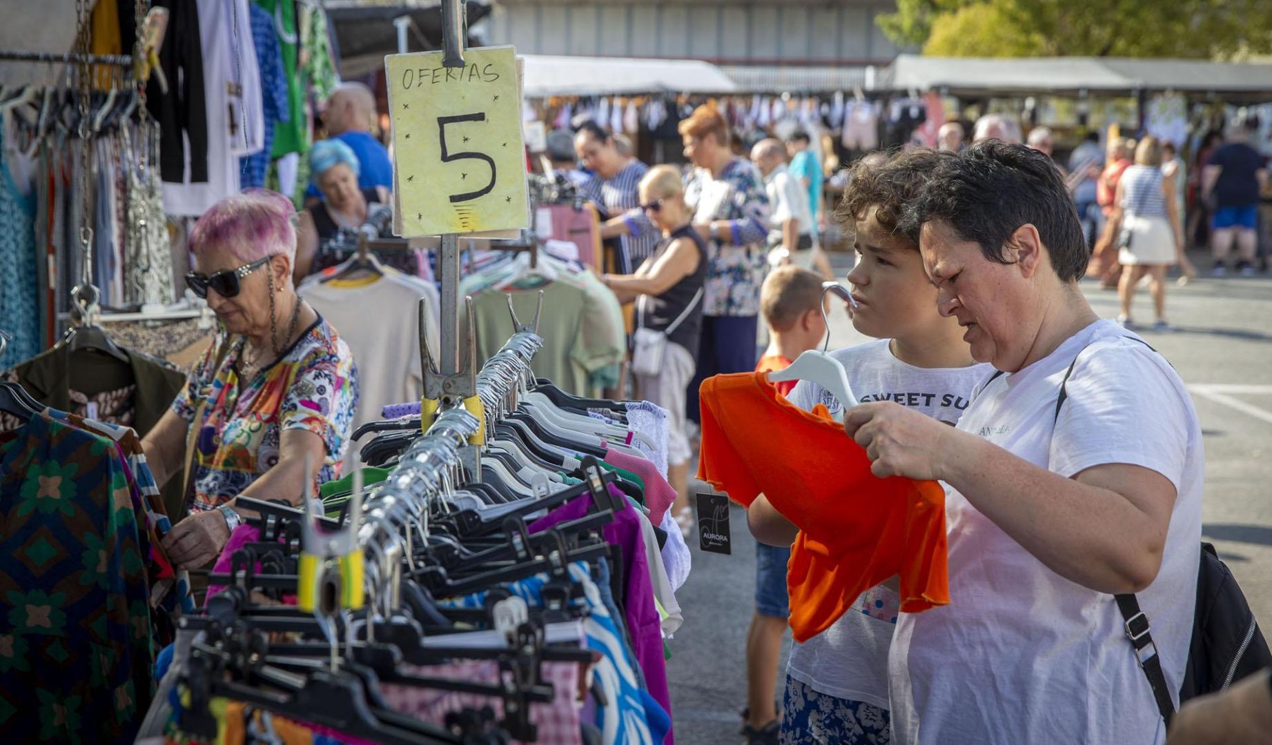 Jóvenes y no tan jóvenes curiosean un puesto de ropa del mercadillo de Landaben