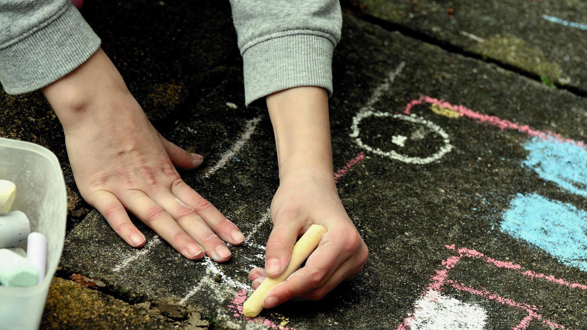 Un niño pintando en el suelo con unas tizas