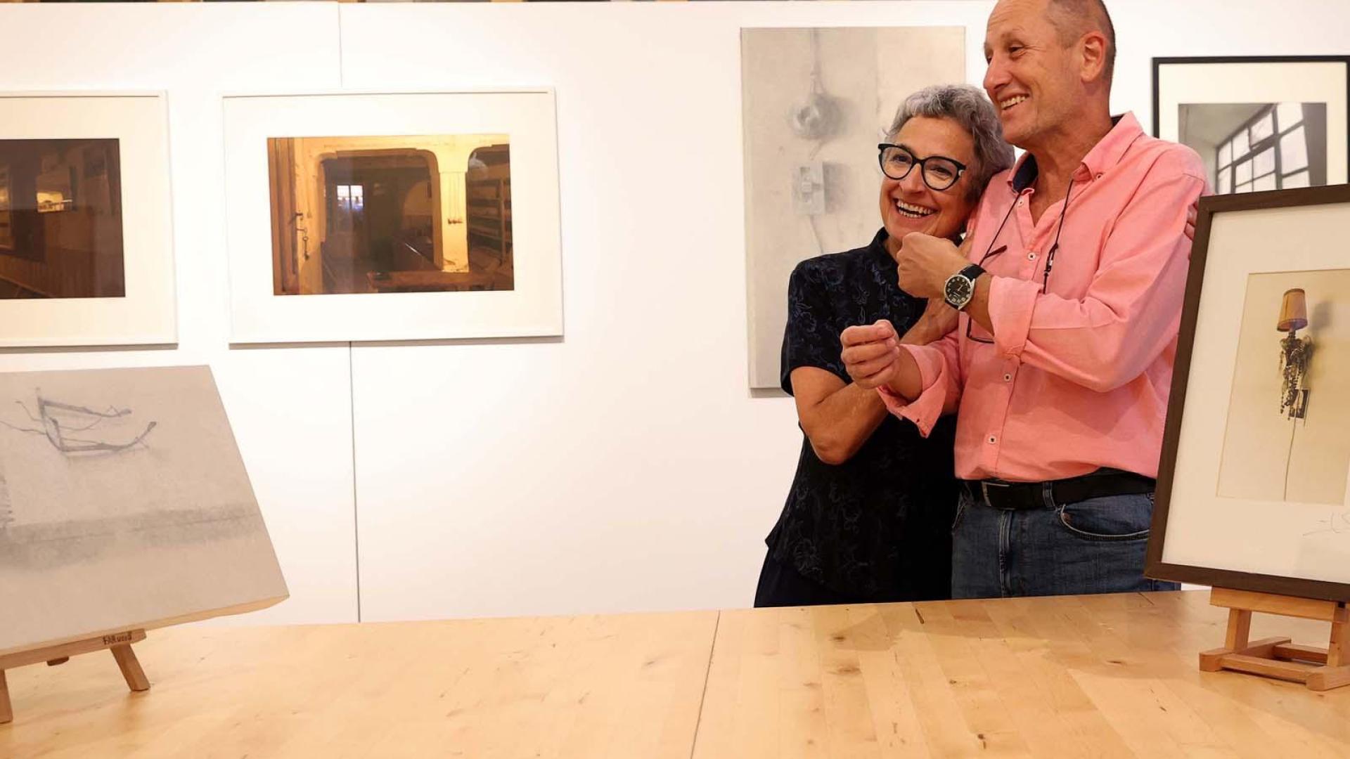 La fotógrafa Mar Mateo y el pintor José Ignacio Agorreta se abrazan en La Fábrica de Gomas. A su alrededor, algunos de los cuadros y las fotos que exponen