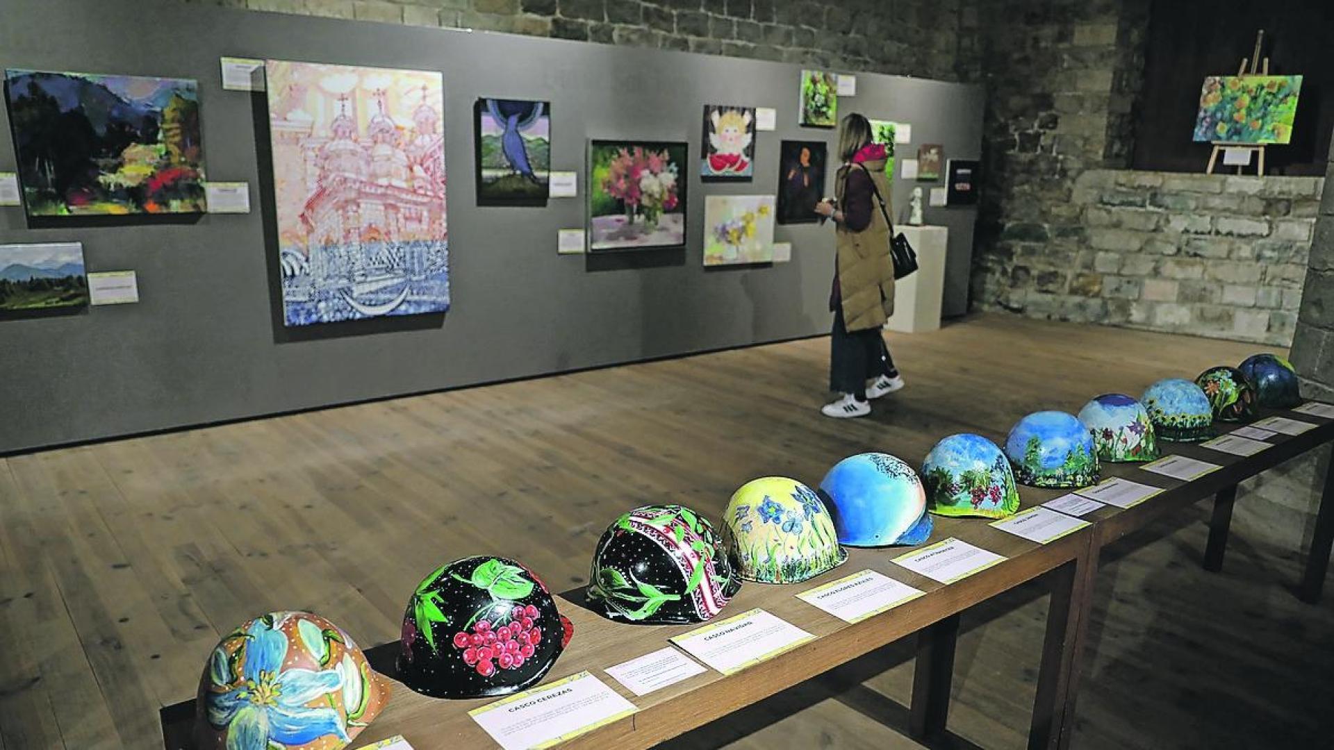 En primer término, los cascos pintados por niños, en la exposición Artistas de la guerra.