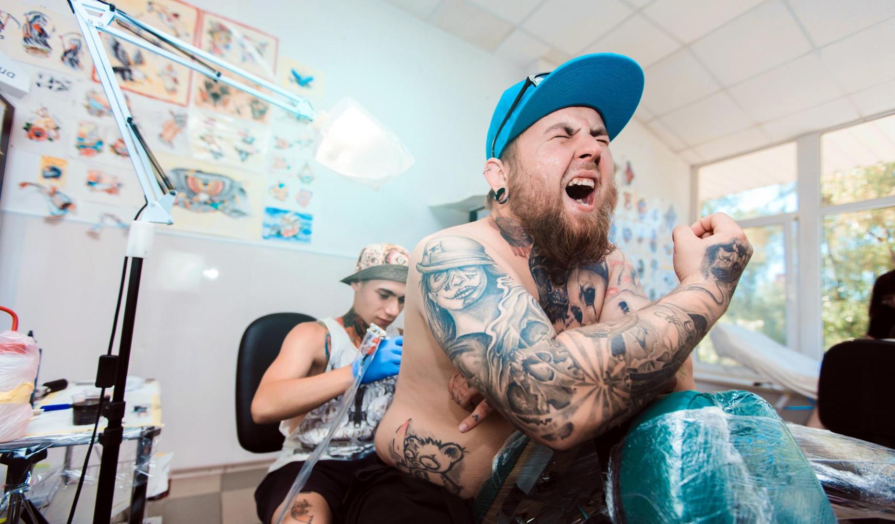 Un tatuador realiza un tatuaje en la espalda de un cliente