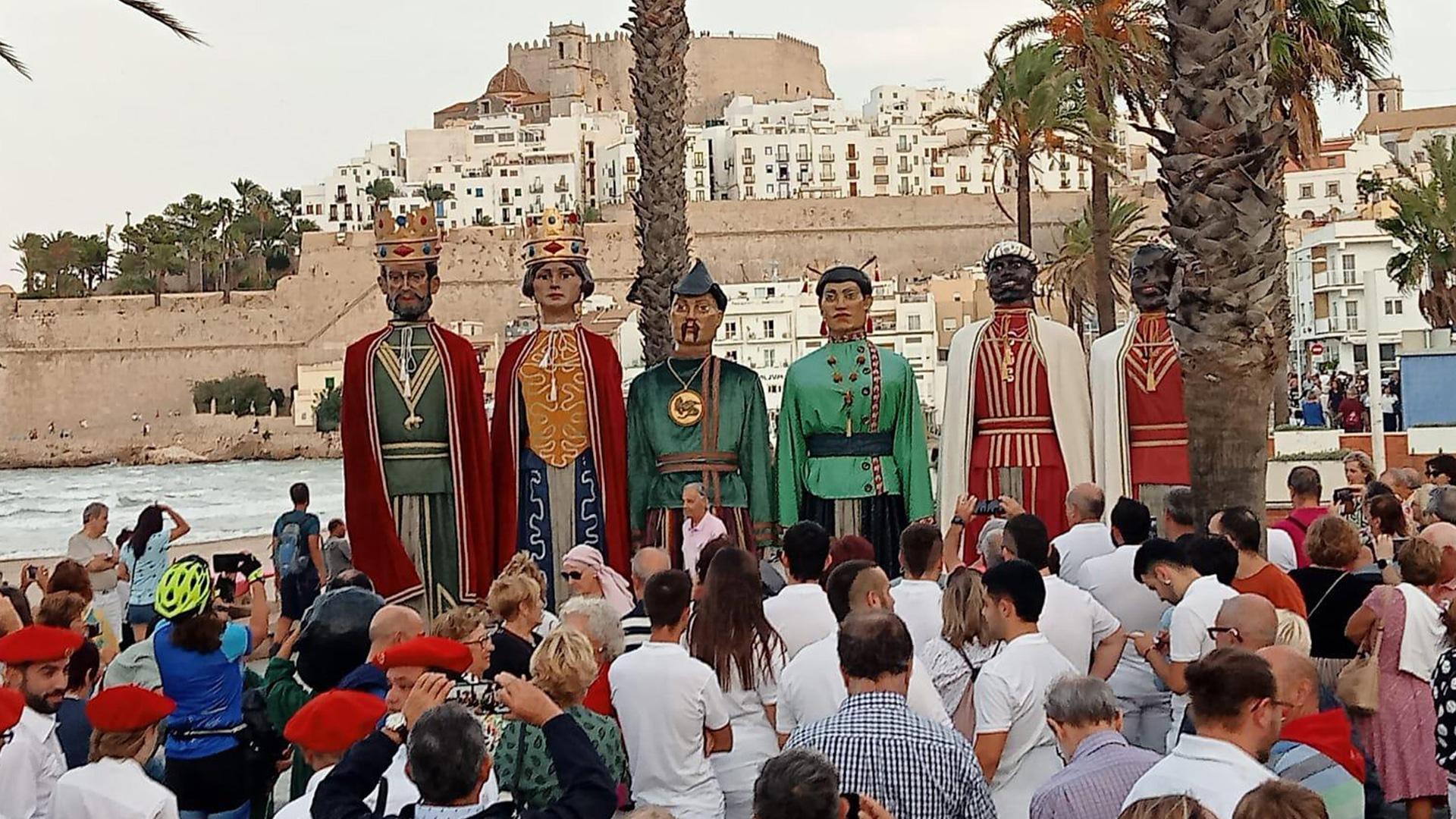 Turistas que se toparon con la comparsa fotografían a los gigantes con el castillo de Peñíscola al fondo