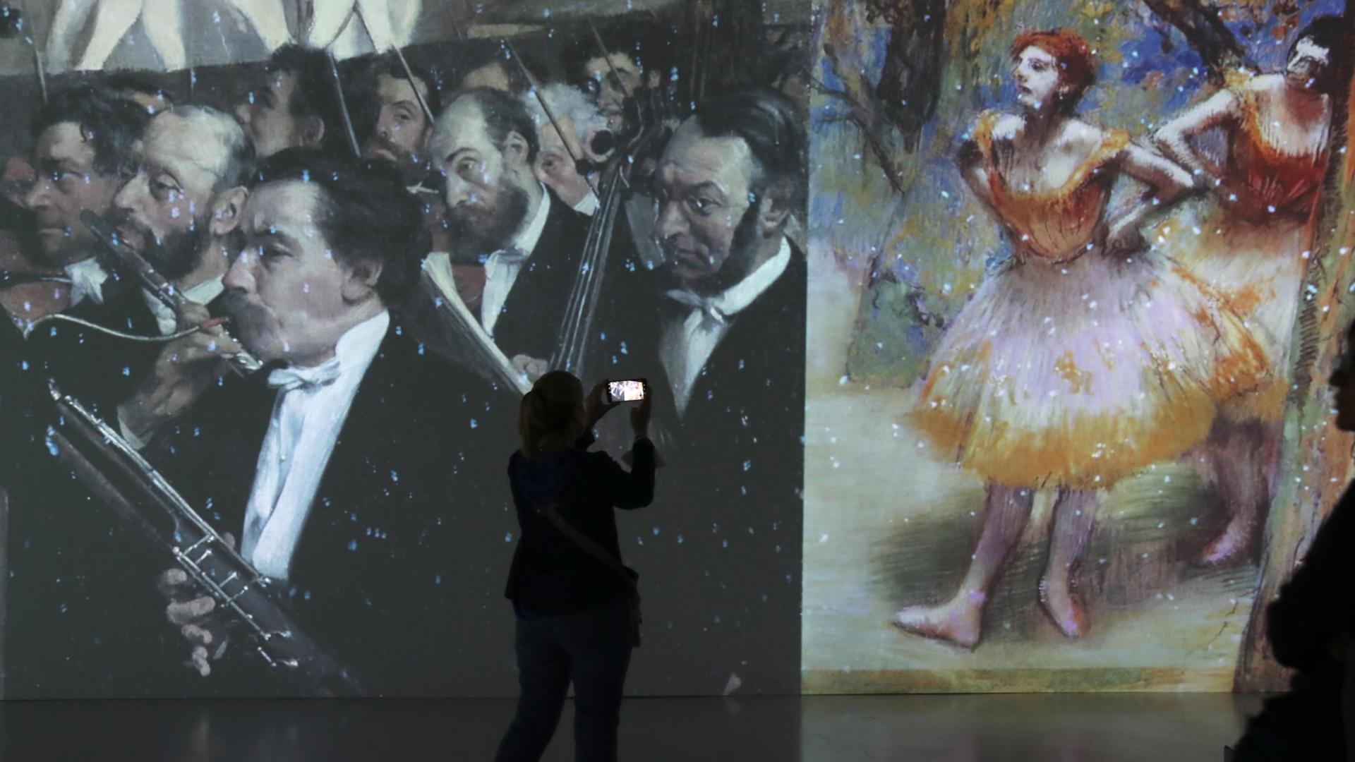 Pantallas gigantes proyectan imágenes en movimiento de las obras, como estas de Degas