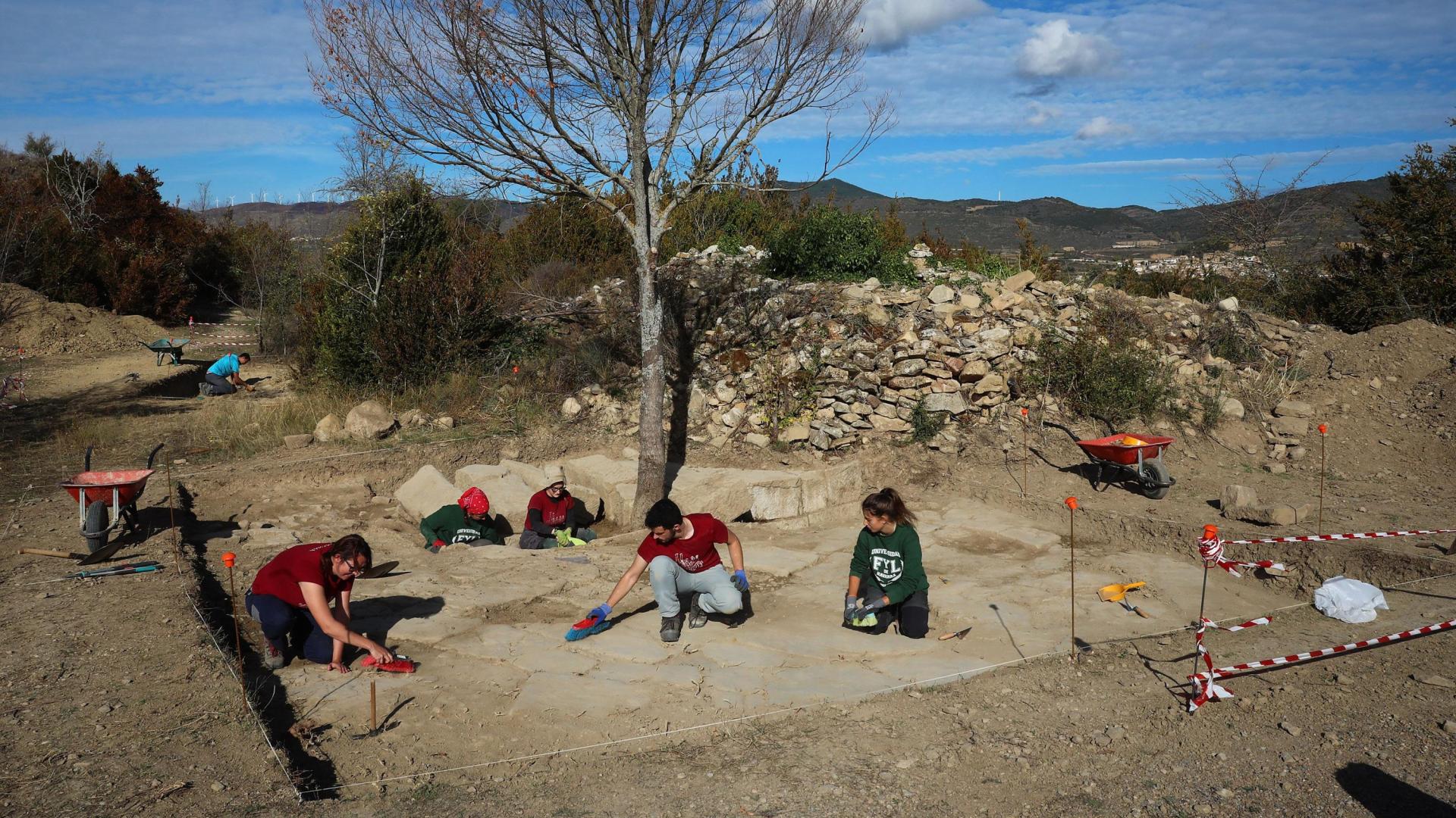 Paloma Lorente (izq.), directora técnica de la excavación, trabajando el pasado lunes en la plaza del Foro de Santa Criz junto a varios alumnos del Diploma de Arqueología de la Universidad de Navarra. Al fondo, el nuevo sondeo que se ha abierto en esta campaña.