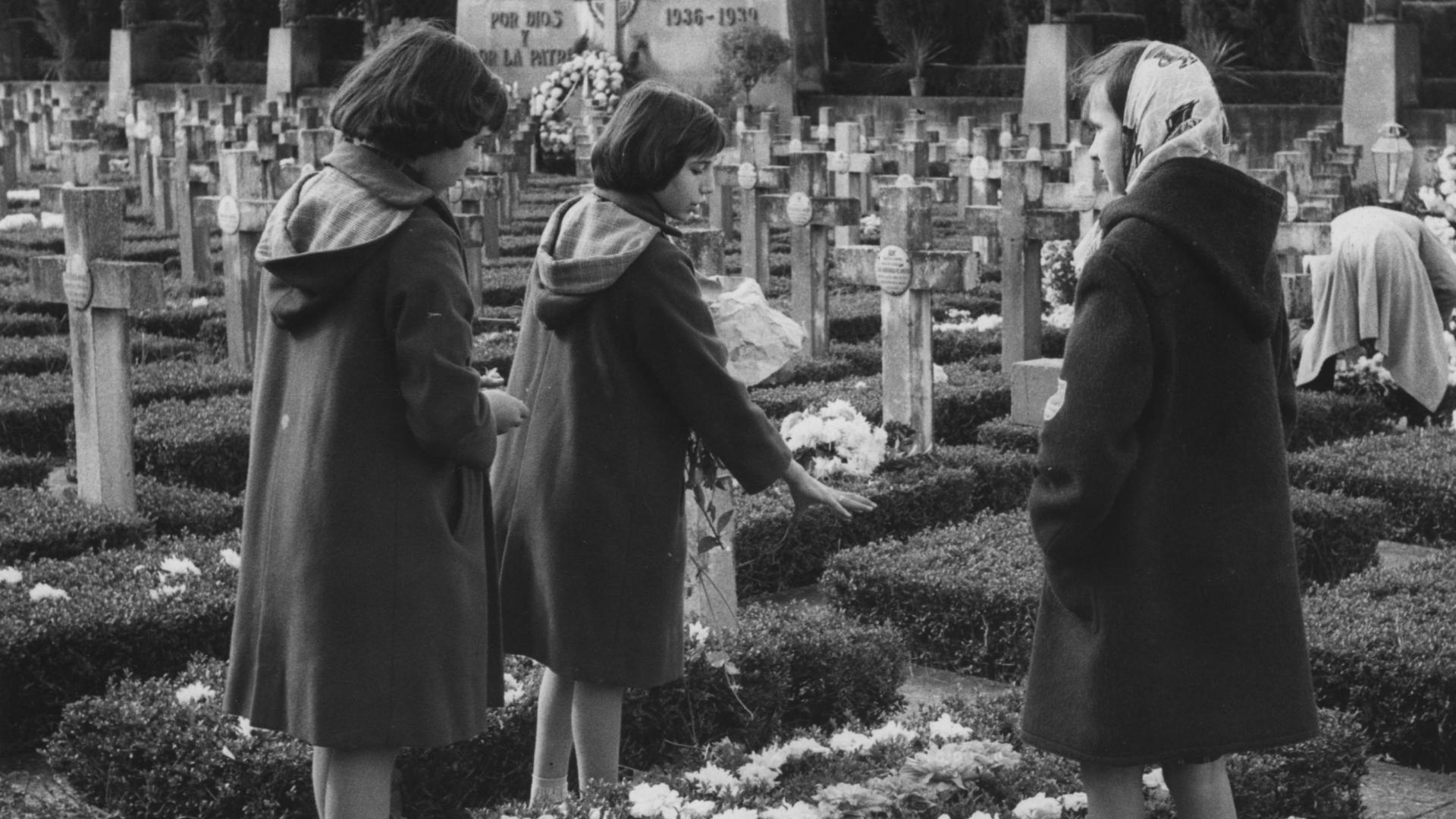 Tres niñas rodean una tumba en el cementerio de Pamplona en la festividad de Todos los Santos de 1959