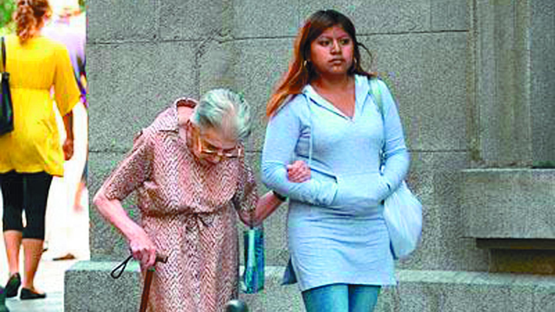 Una joven latina acompaña del brazo a una señora mayor por la calle