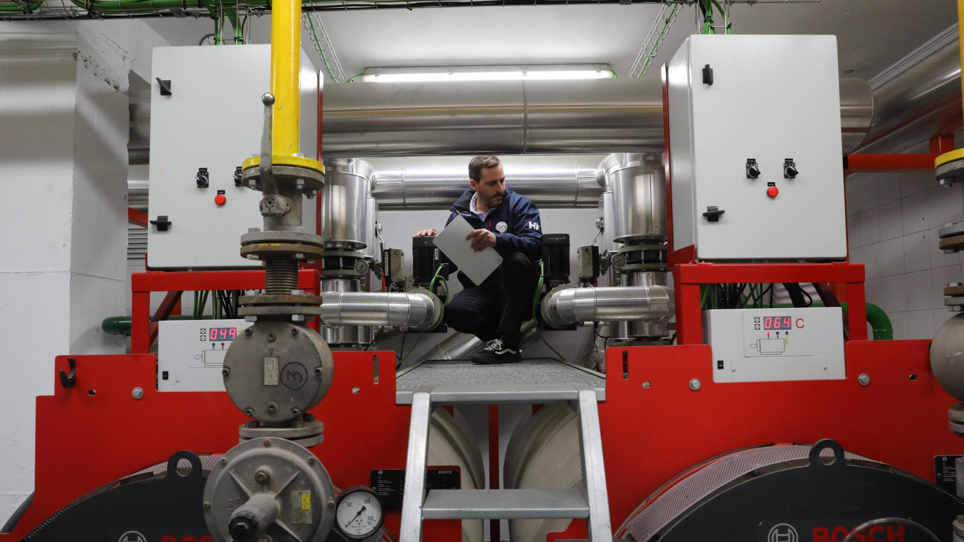 Un técnico revisa la sala de caldera de una comunidad con calefacción central.
