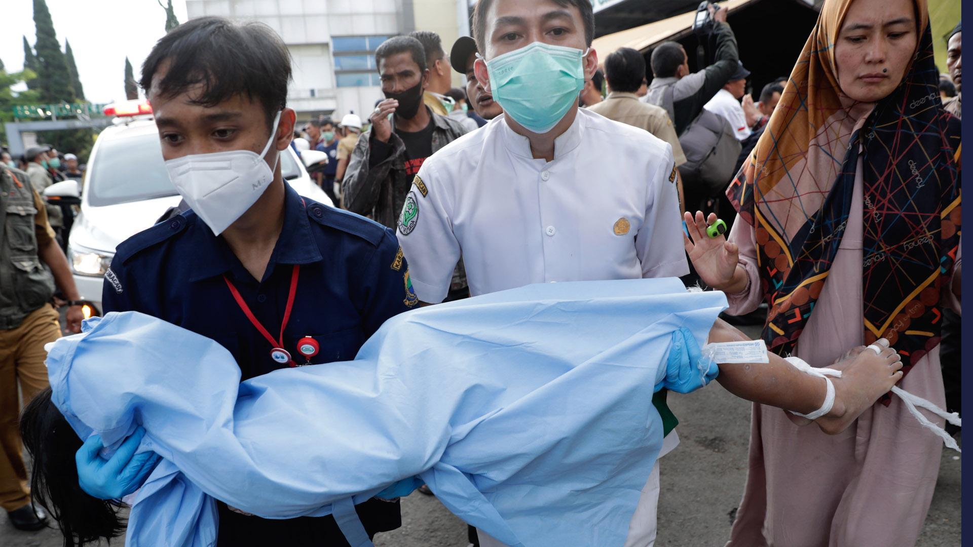 Rescatadores y una madre trasladan el cuerpo de un niño, víctima del terremoto