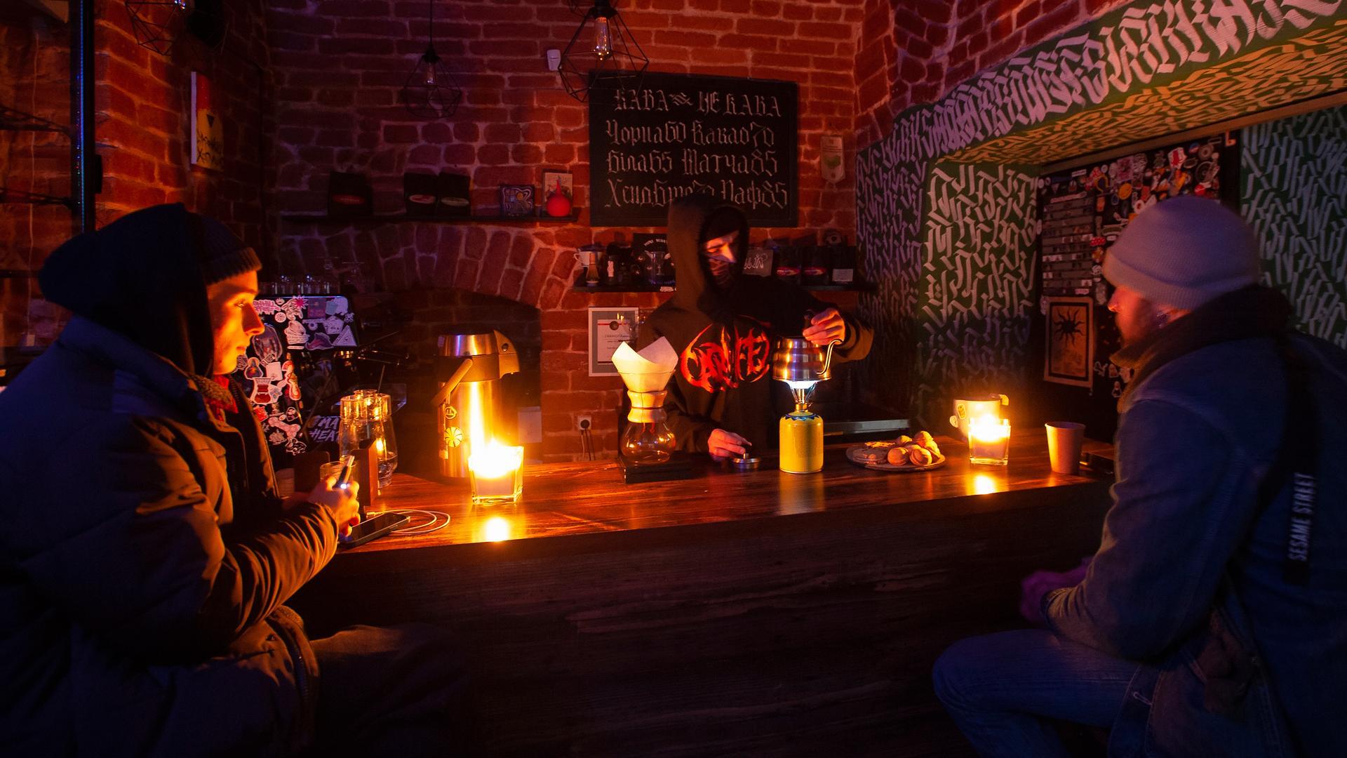 Varias personas se iluminan con velas en un restaurante en el oeste de Ucrania, en la ciudad de Lviv, como consecuencia de los cortes de luz por los ataques rusos
