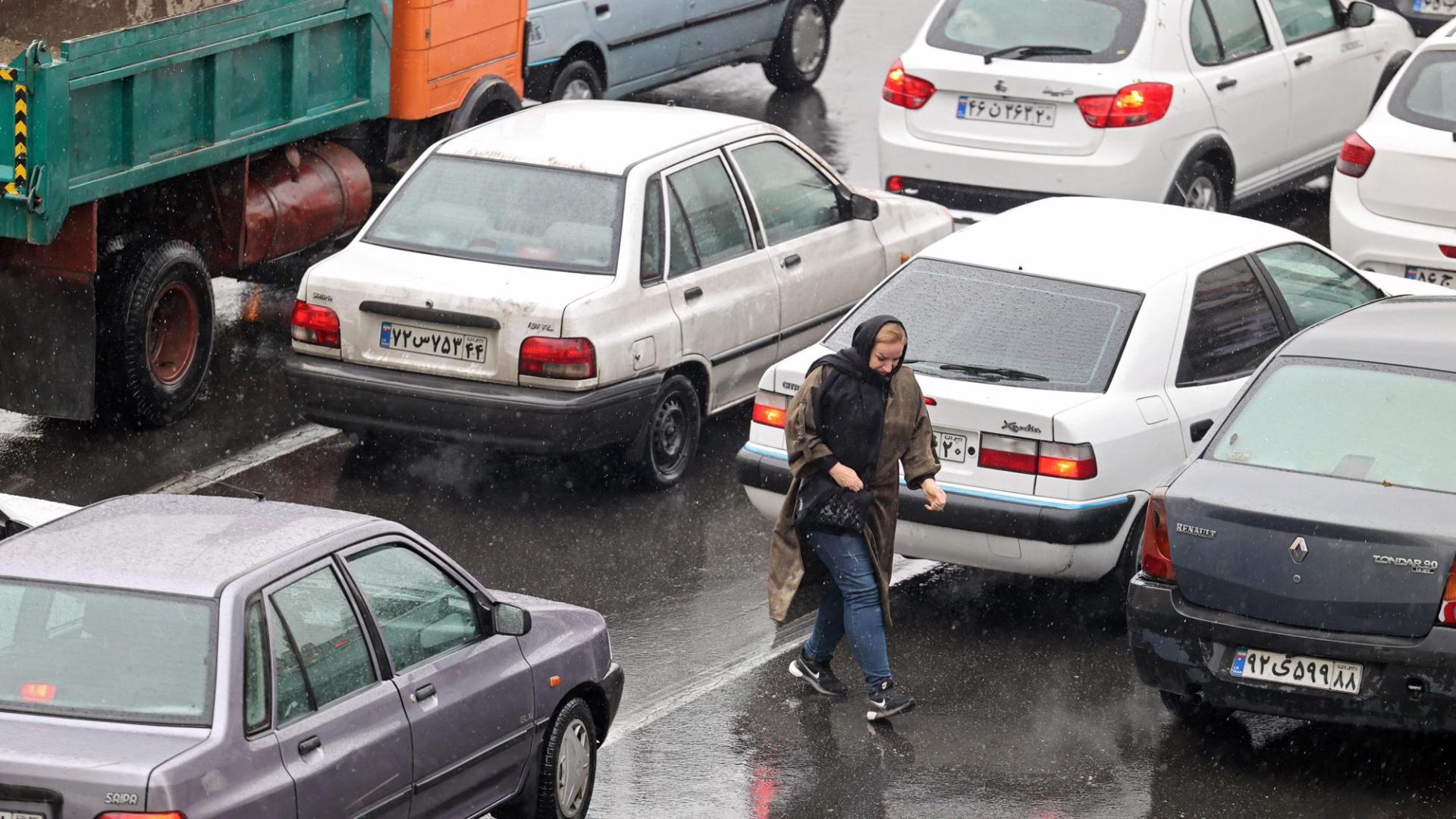 Una mujer camina entre los coches en Teherán, Irán
