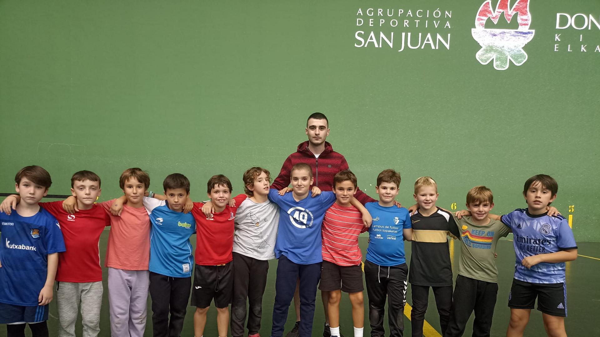 Una docena de pelotaris de la escuela de pelota a mano posan junto al técnico del club Iker Fernández.