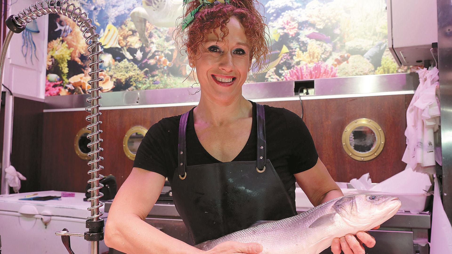 Comerciante del Mercado del Ensanche muestra un ejemplar de pescado