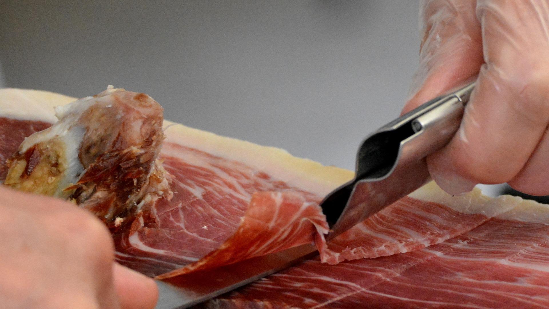 Imagen de archivo de una persona cortando un jamón