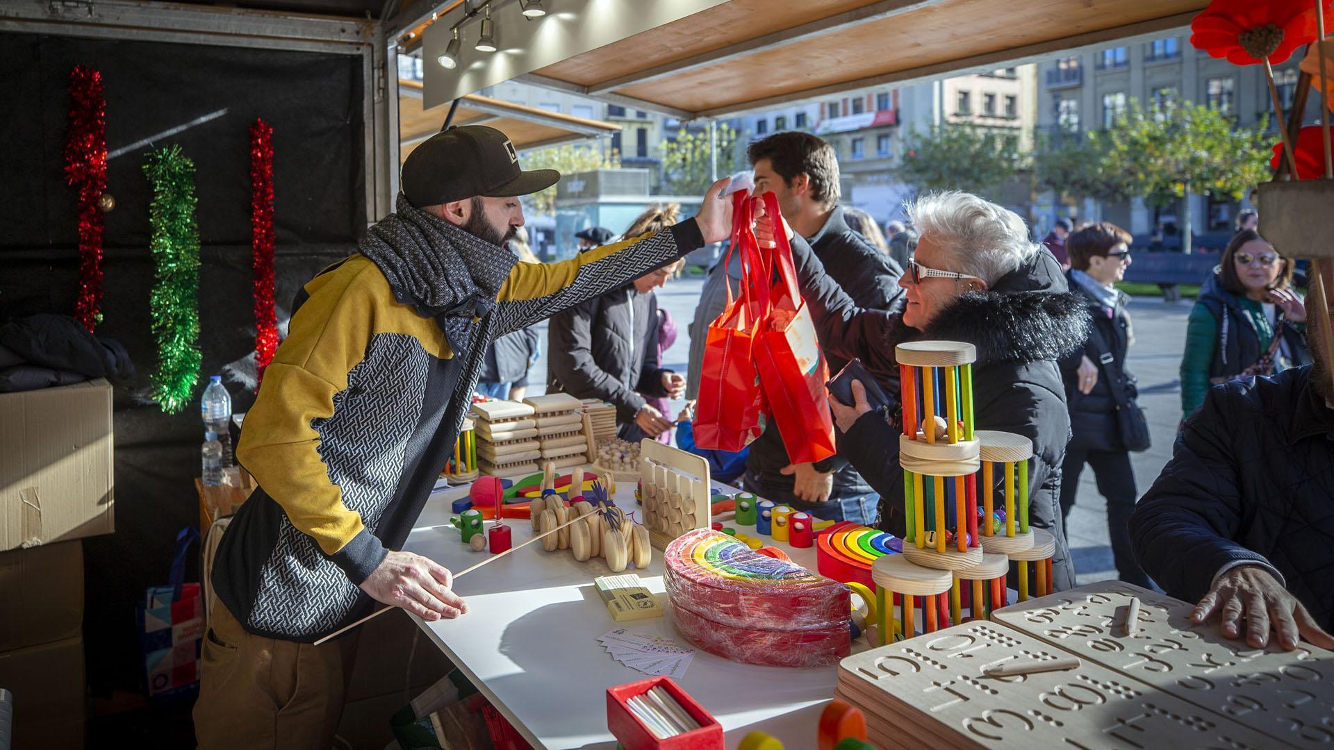 Uno de los comerciantes atiende a varios clientes en la Feria de Navidad