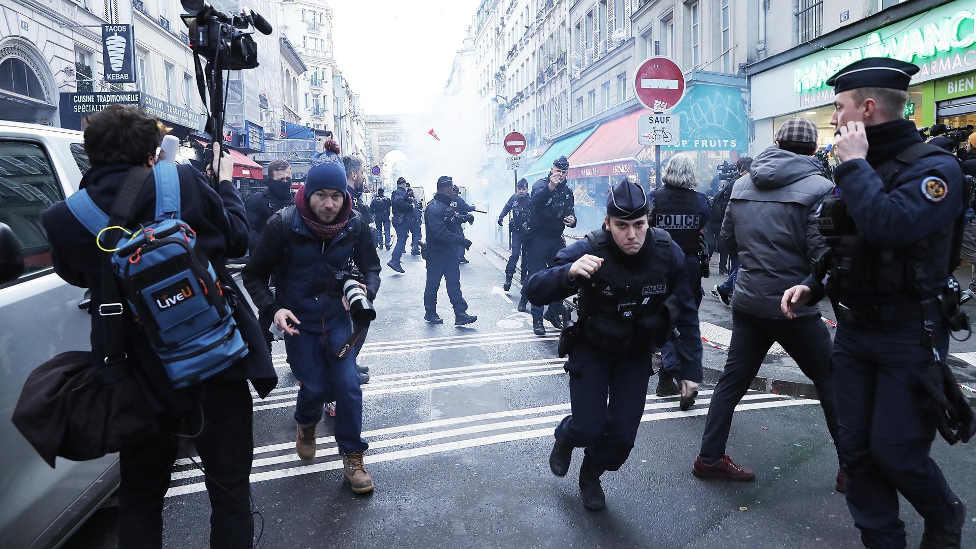 Policías y protestantes durante los disturbios de este vuiernes en París.