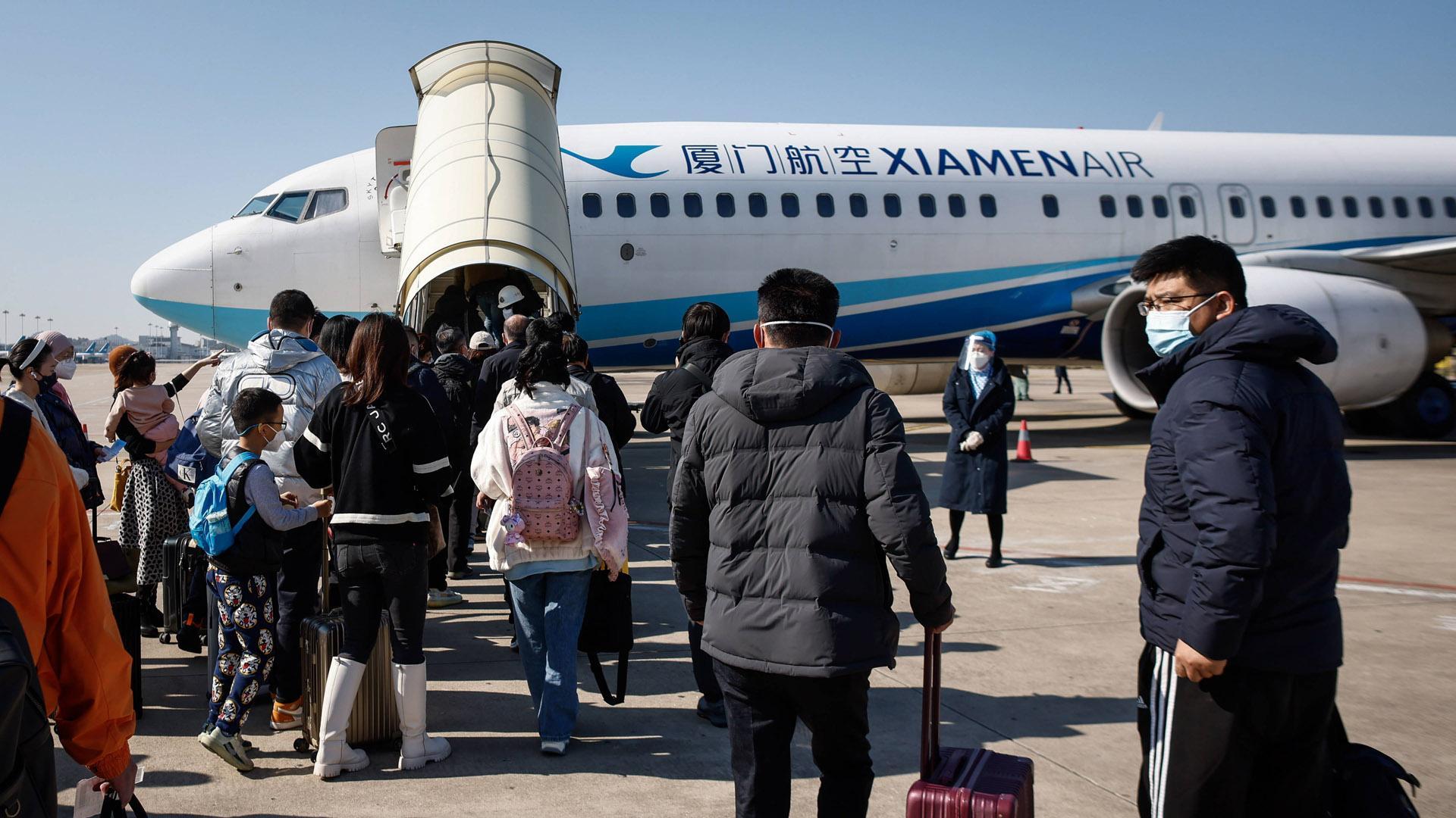 Pasajeros se dirigen por las pistas al avión que les llevará desde del aeropuerto de Xiamen a Pekín