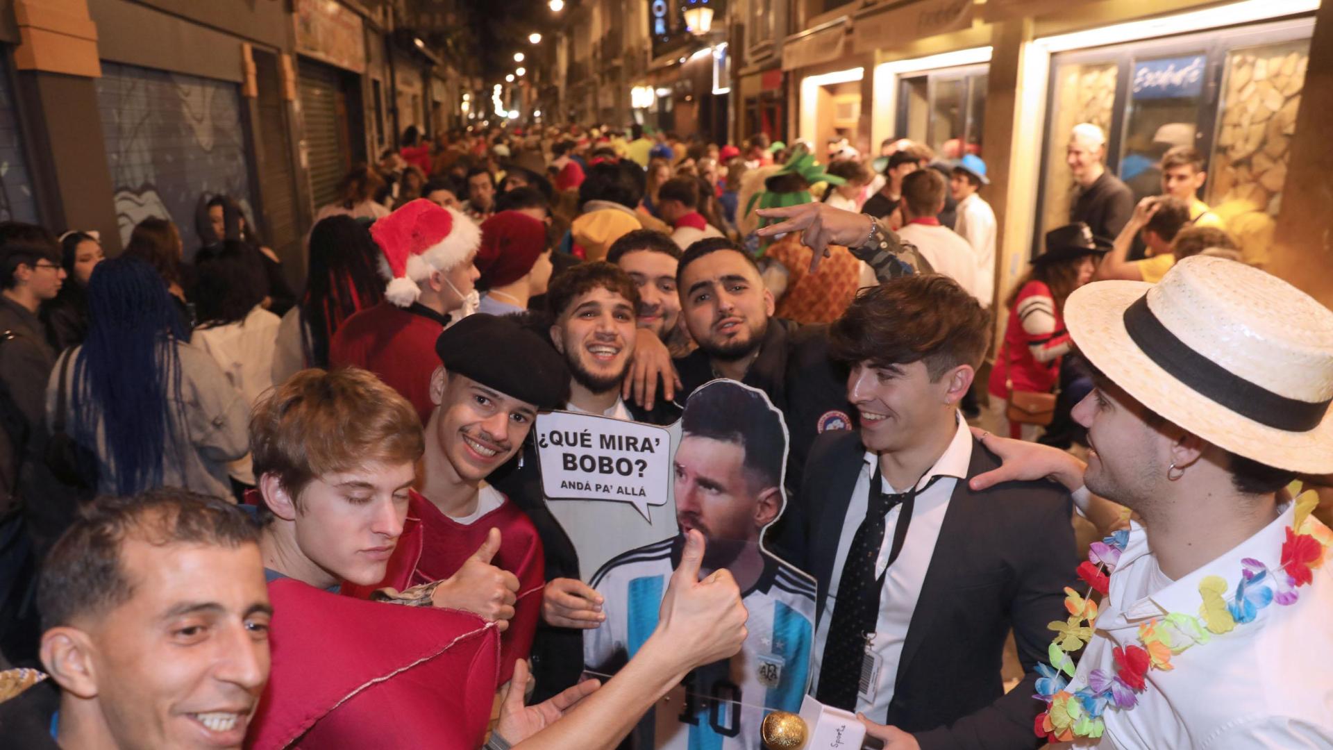 Mikel Aceldegui, con camisa y corbata, junto con su cartel de Messi en la calle San Nicolás, uno de los lugares más concurrido de la noche