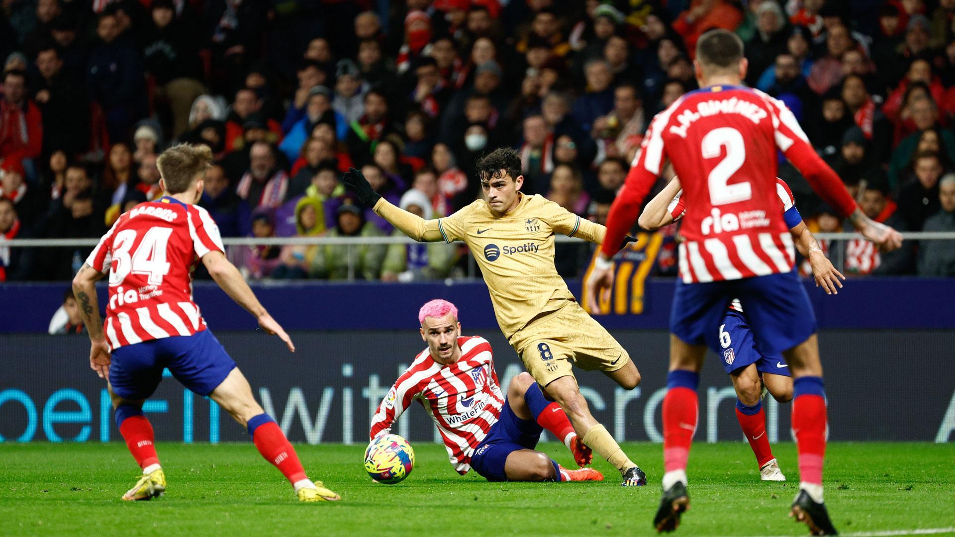 El centrocampista del FC Barcelona, Pedri, se lleva el balón ante el delantero francés del Atlético de Madrid, Antoine Griezmann
