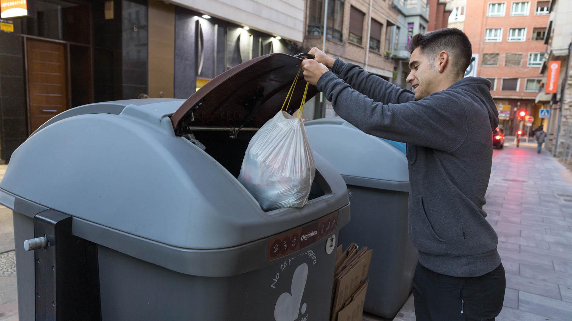 Un joven introduce una bolsa en el contenedor marrón para materia orgánica de la calle Capuchinos de Tudela