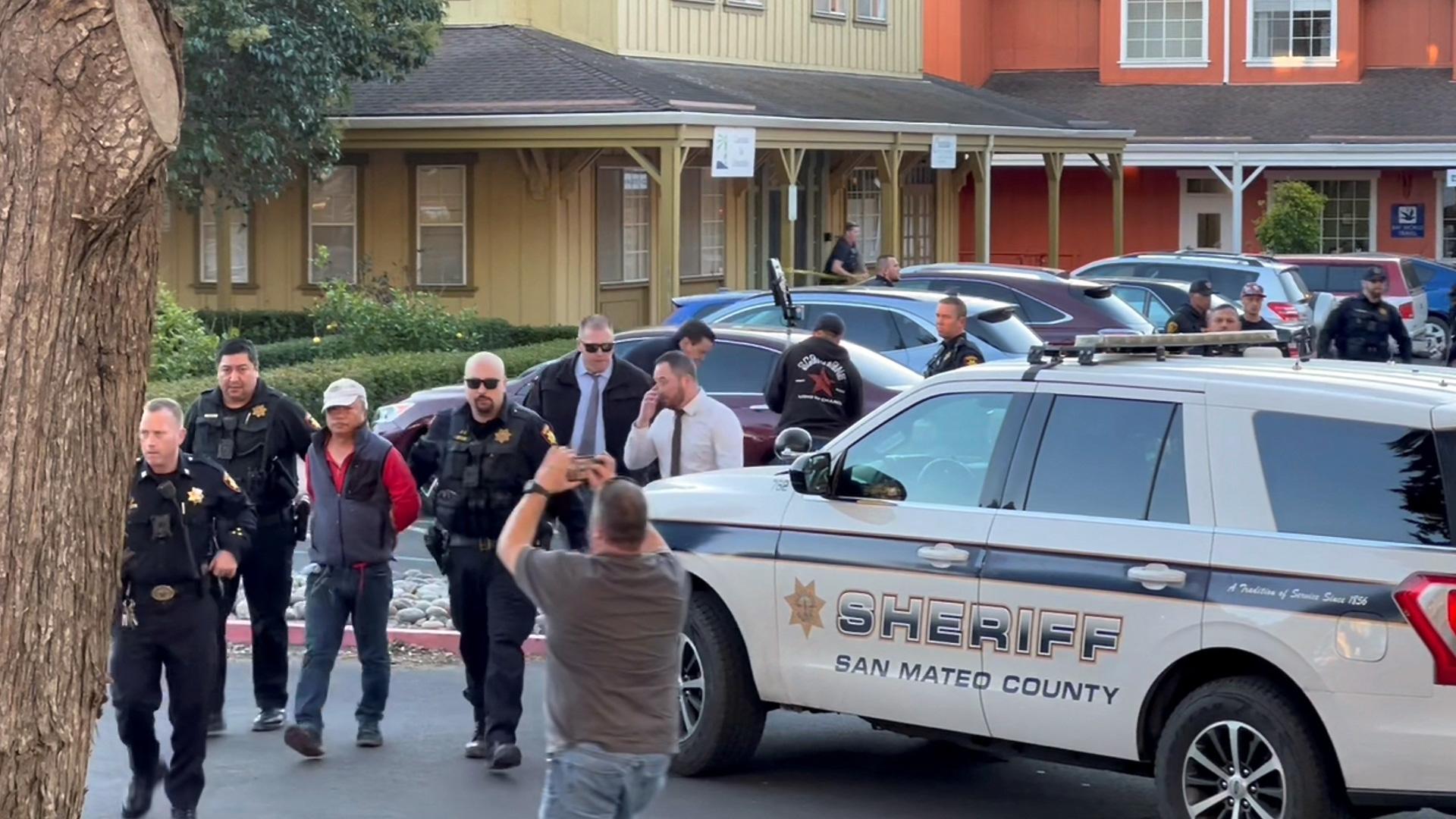 Agentes de la Policía con un hombre detenido tras el tiroteo en Half Moon Bay, en California