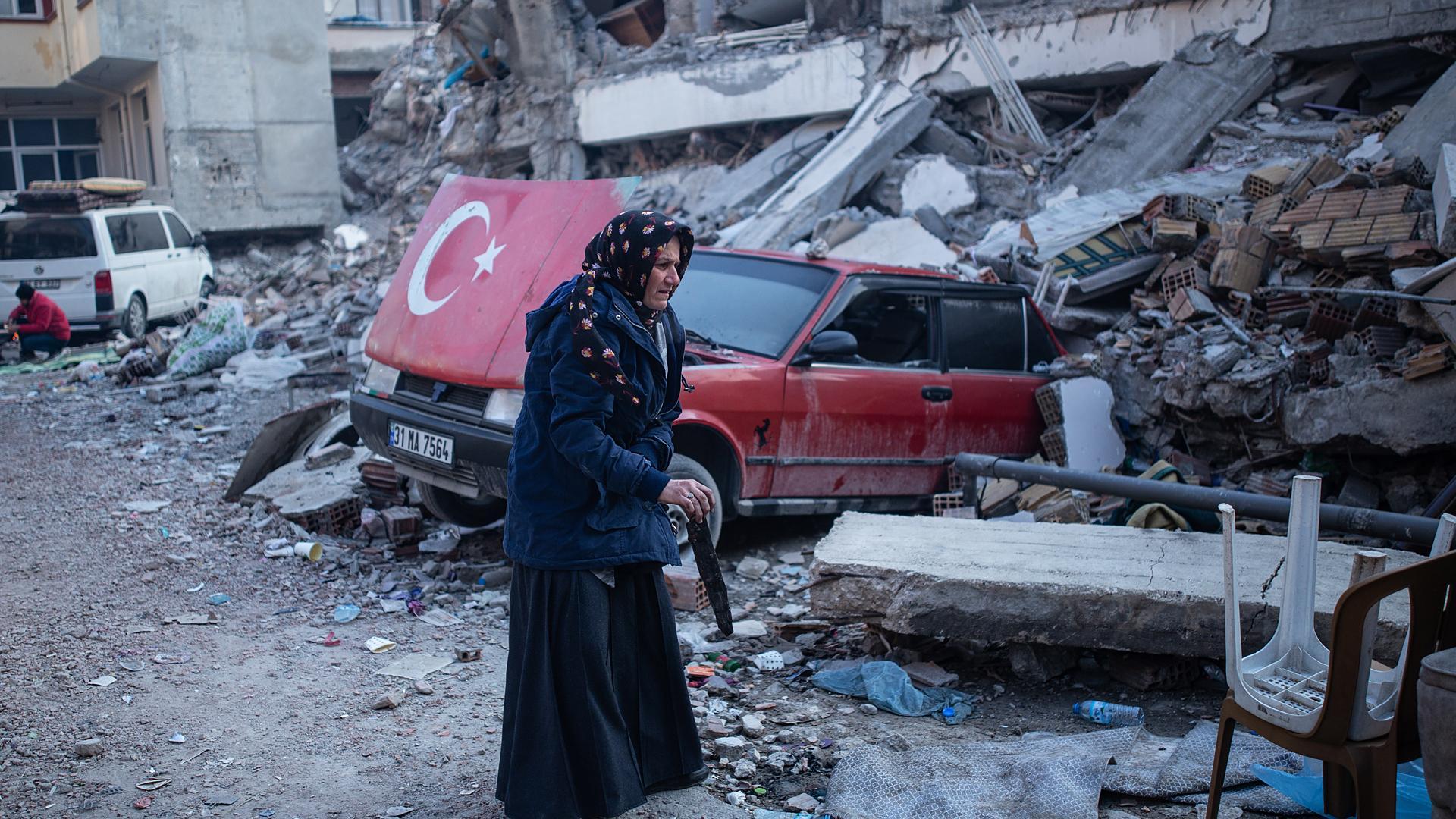 Una anciana camina entre los escombros de un edificio derribado por el terremoto en la localidad turca de Hatay.