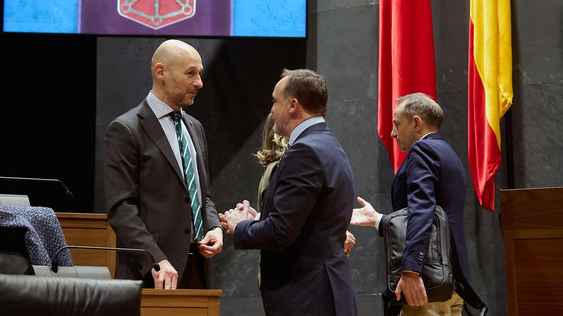 Los parlamentarios de Navarra Suma Iñaki Iriarte (izda.) y Javier Esparza conversan  durante el pleno de este jueves en el Parlamento foral