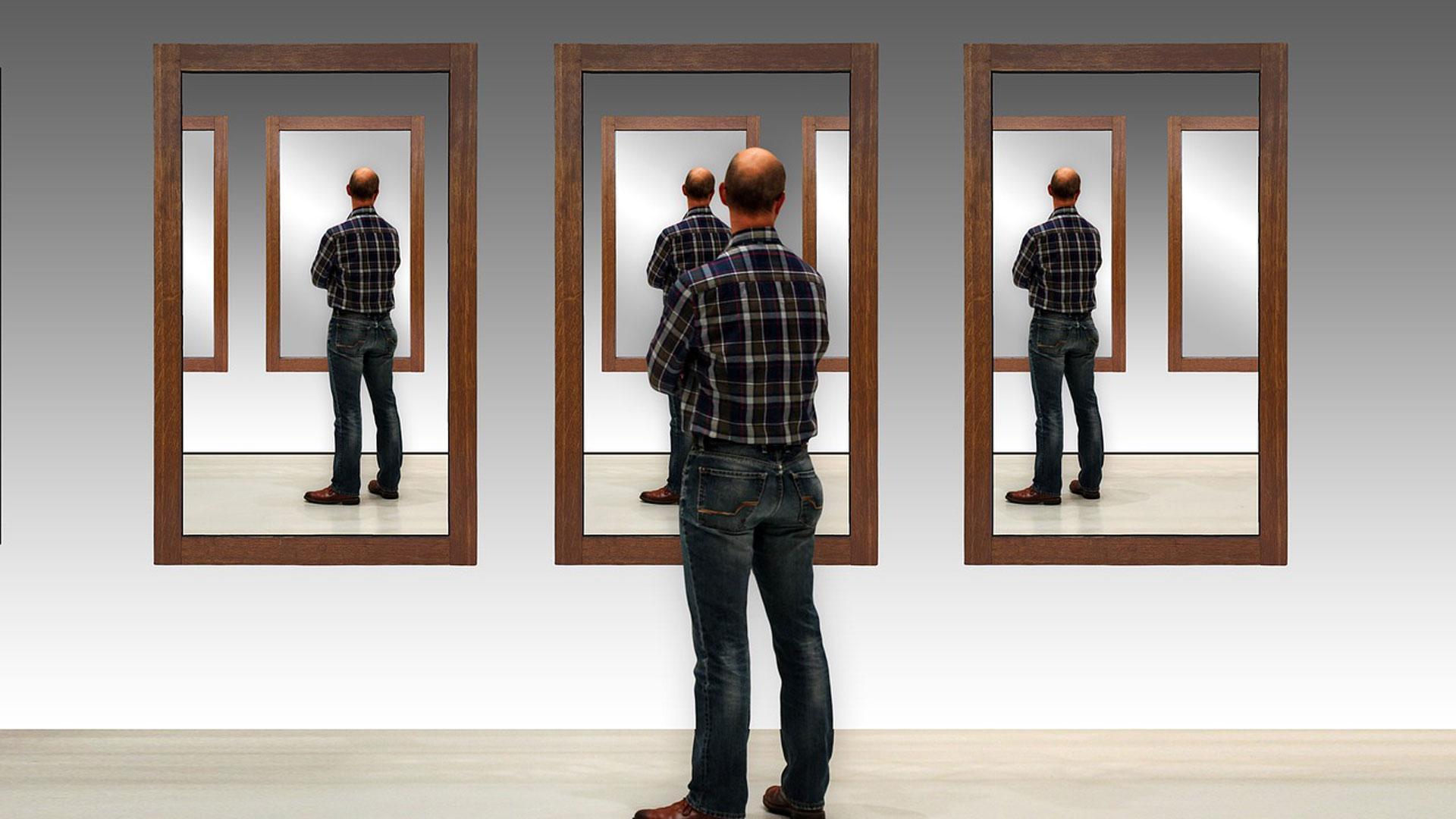 Un hombre observa su imagen repetida en varios espejos