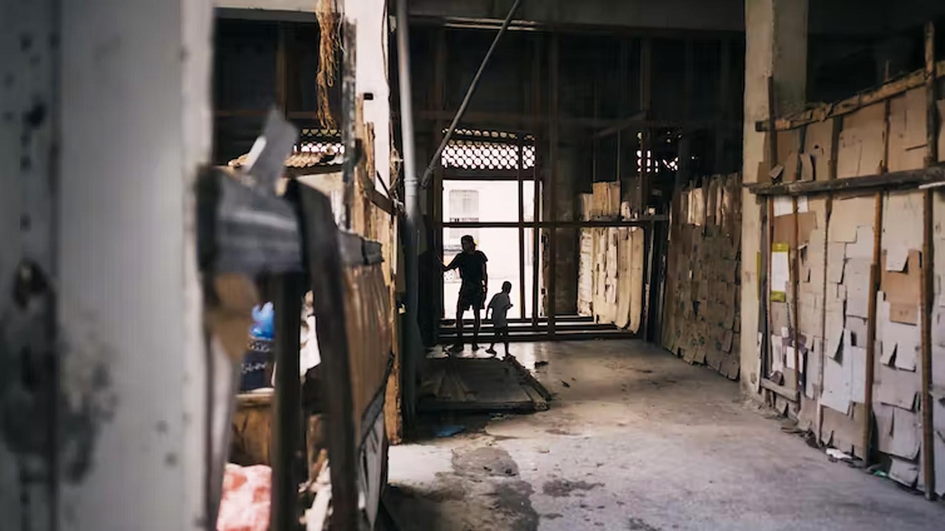 Un joven cubano y un niño juegan en el pasillo de un edificio abandonado - La Habana, Cuba, diciembre de 2022.