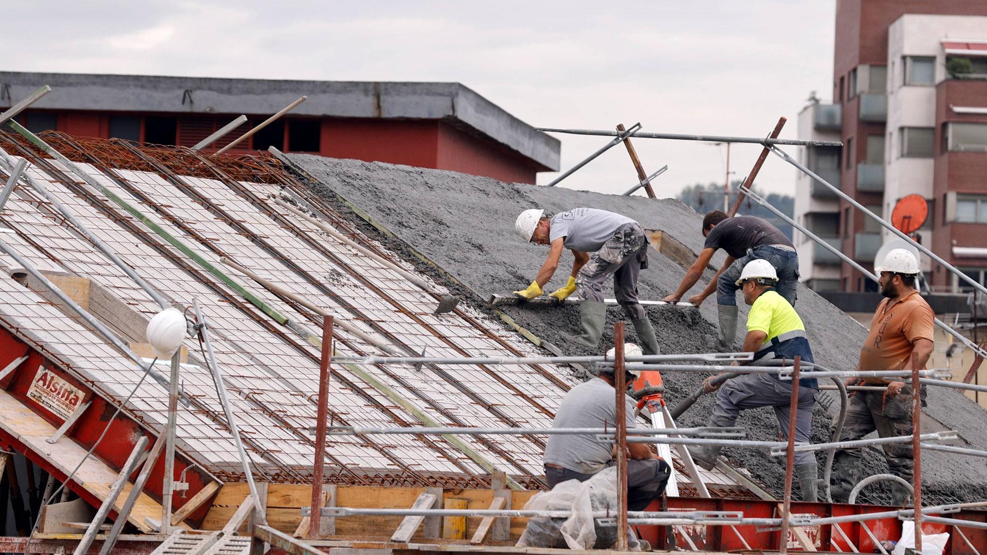 Varios empleados de la construcción trabajan en el tejado de un edificio