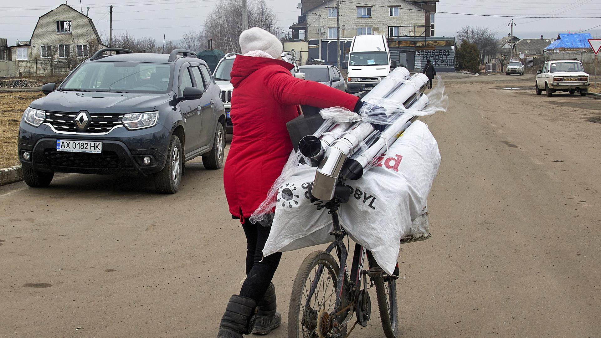 Una mujer transporta elementos de una calefacción repartidos entre la población para combatir el frío en la localidad ucraniana de Kharkiv.