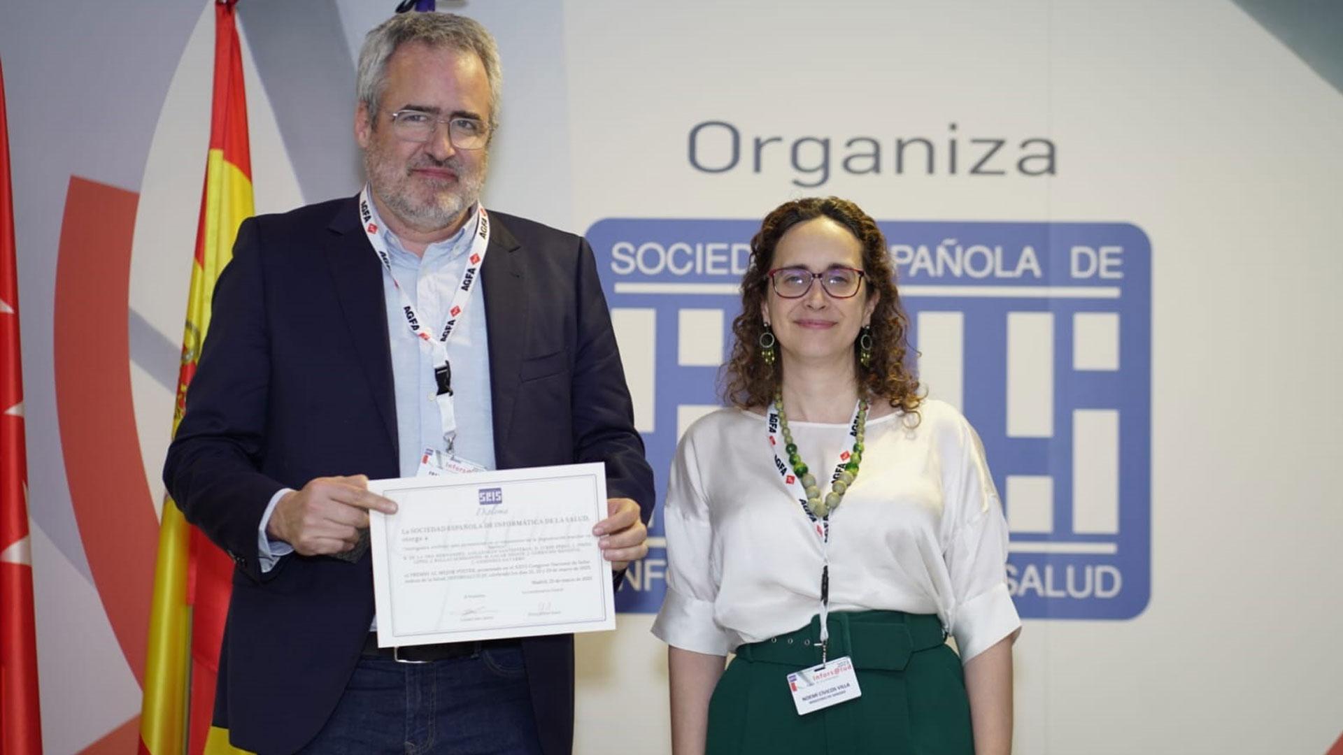 Javier Turumbay, subdirector de Sistemas y Tecnologías para la Salud del SNS- Osasunbidea, y Noemi Civicos, directora general de Salud Digital y Sistemas de Información para el SNS en Ministerio de Sanidad, con el poster