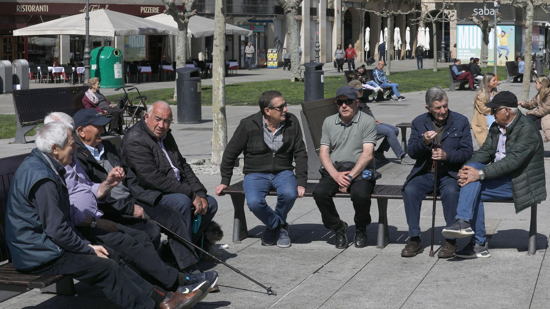 Dos grupos de hombres charlan al sol en la Plaza del Castillo de Pamplona