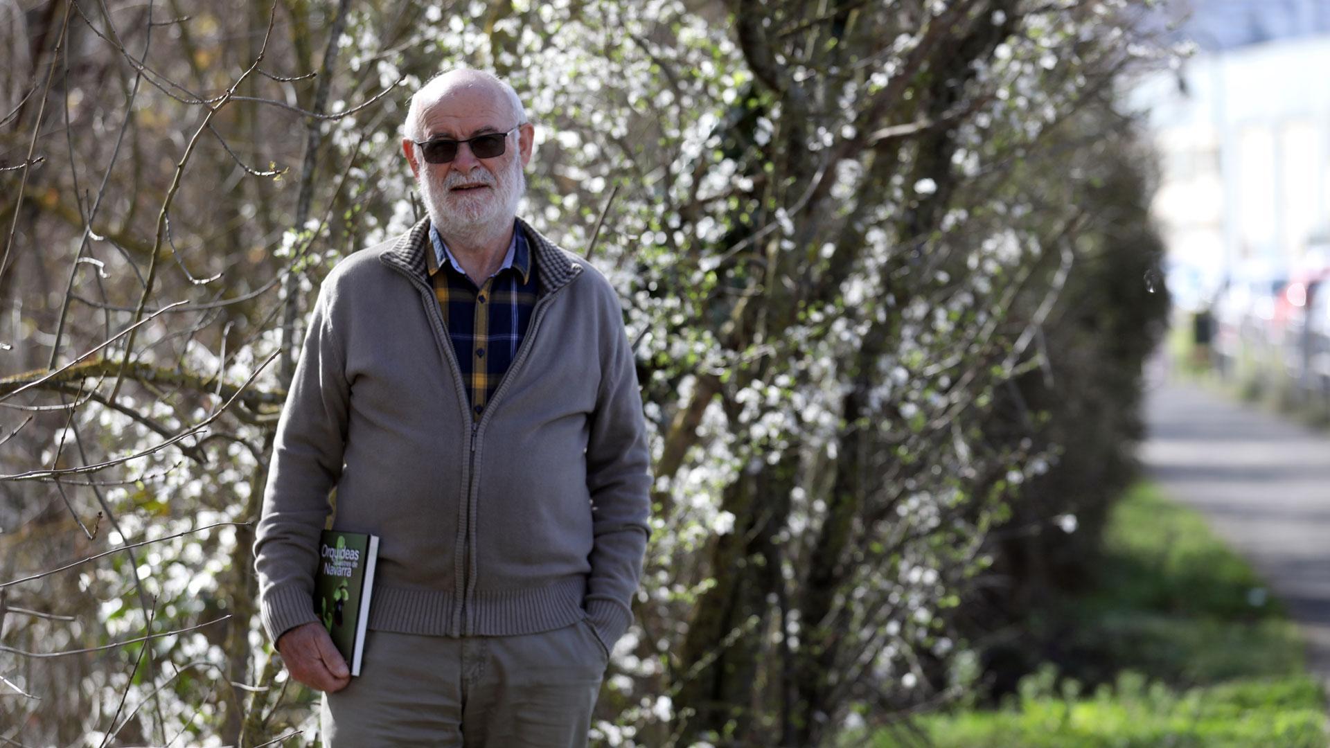 Cruz Miguel Babace posa en un paraje del paseo del Arga en el polígono de Landaben en Pamplona. Sostiene el libro de orquídeas silvestres de Navarra del que es coautor