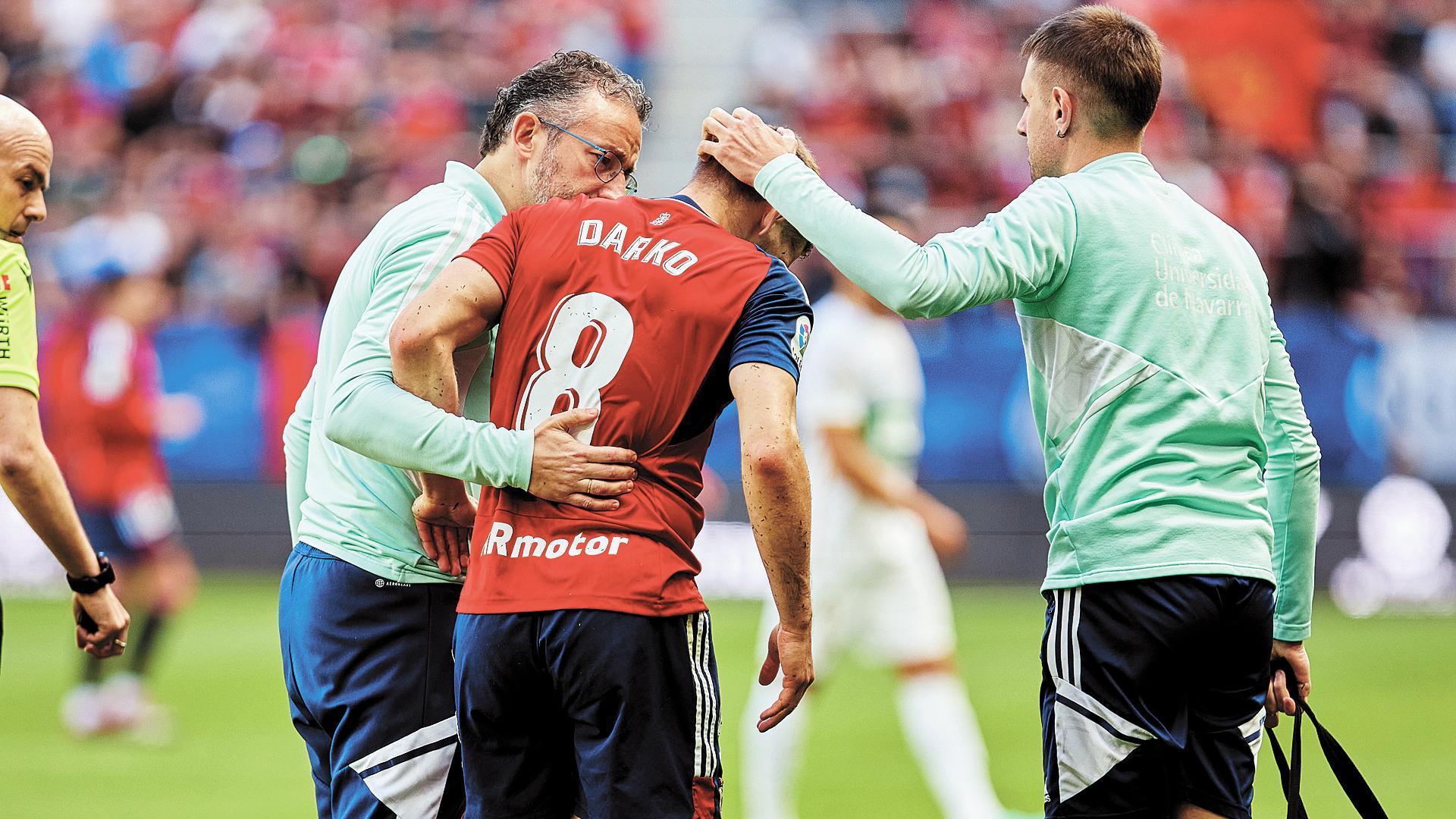 Darko Brasanac en el momento de retirarse del terreno de juego junto al doctor Andrés Valentí (izquierda) y el fisio Asier Urkia.
