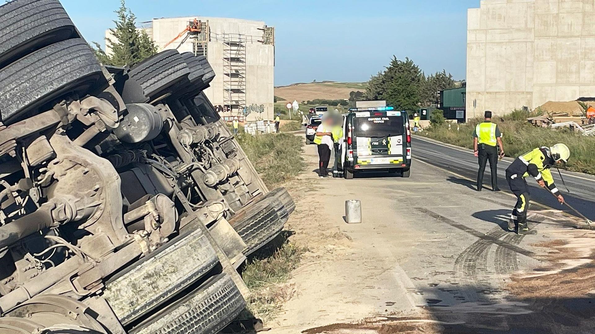 Agentes de la Guardia Civil regulan el tráfico mientras efectivos de Bomberos de Navarra realizan labores de limpieza en la carretera