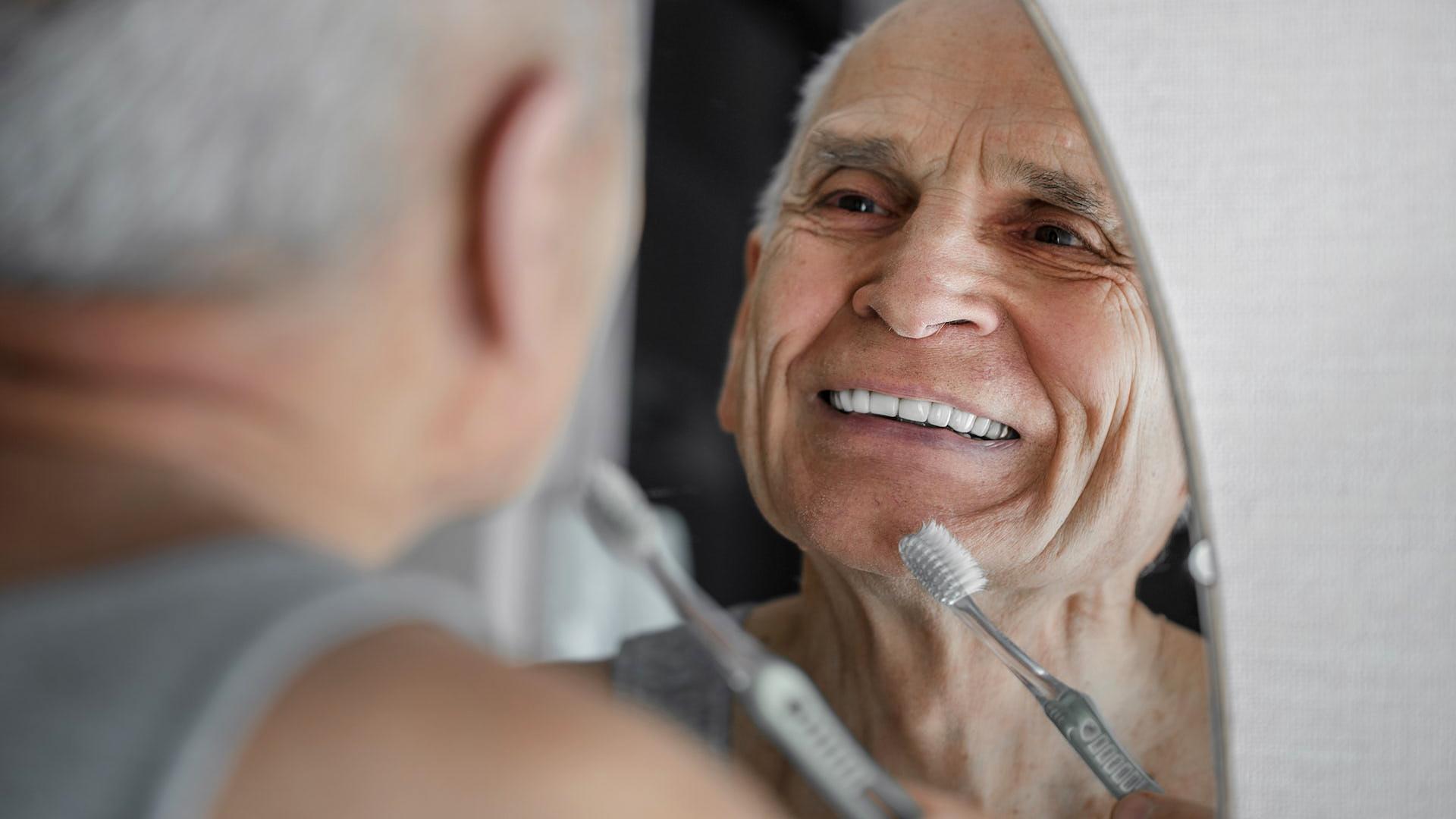 Un hombre observa en el espejo los efectos en sus dientes tras cepillárselos