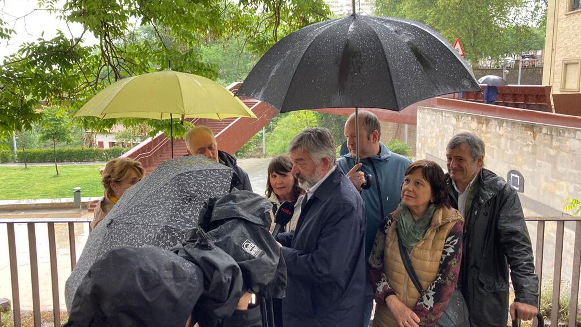 El candidato de Geroa Bai a la Alcaldía de Pamplona, Koldo Martínez, bajo los paraguas en un acto electoral este domingo junto a la pasarela de Labrit de Pamplona