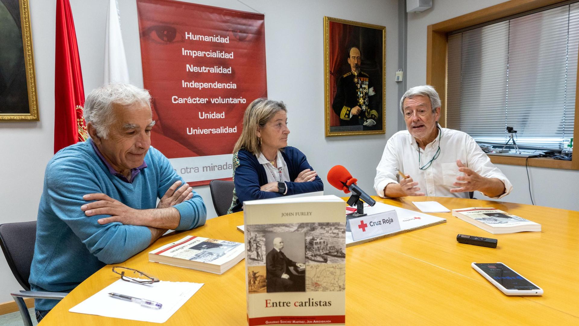 Los estudiosos Guillermo Sánchez (izda) y Jon Arrizabalaga, con la presidenta de Cruz Roja Navarra, Isabel Cadena, en la presentación del libro 'Entre carlistas'.